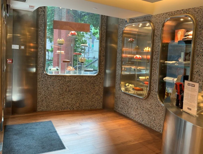 Messina Pattiserie interior by Wan Fang Construction, featuring a window and glass display case showcases colorful cakes and pastries. The modern interior is accented with terrazzo-patterned walls and metallic frames, creating an inviting and contemp