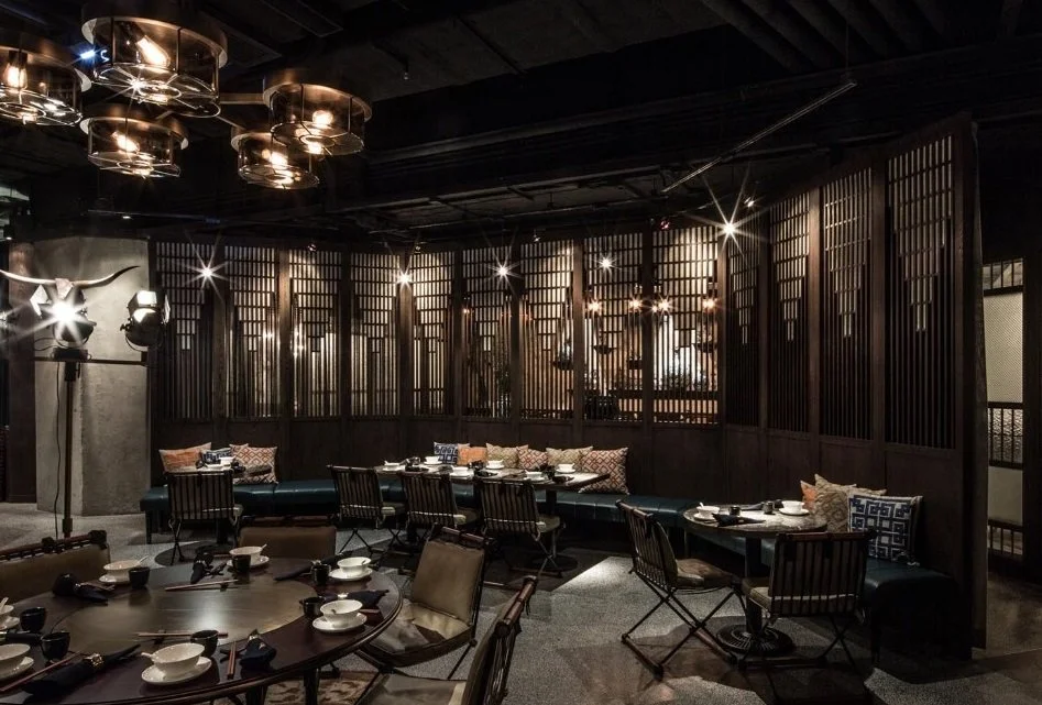 Mott 32, an award-winning Chinese Restaurant, interior dining area by Wang Fang Construction, dark tables set for dining, and a mix of modern and rustic decor, in Hong Kong Central. 
