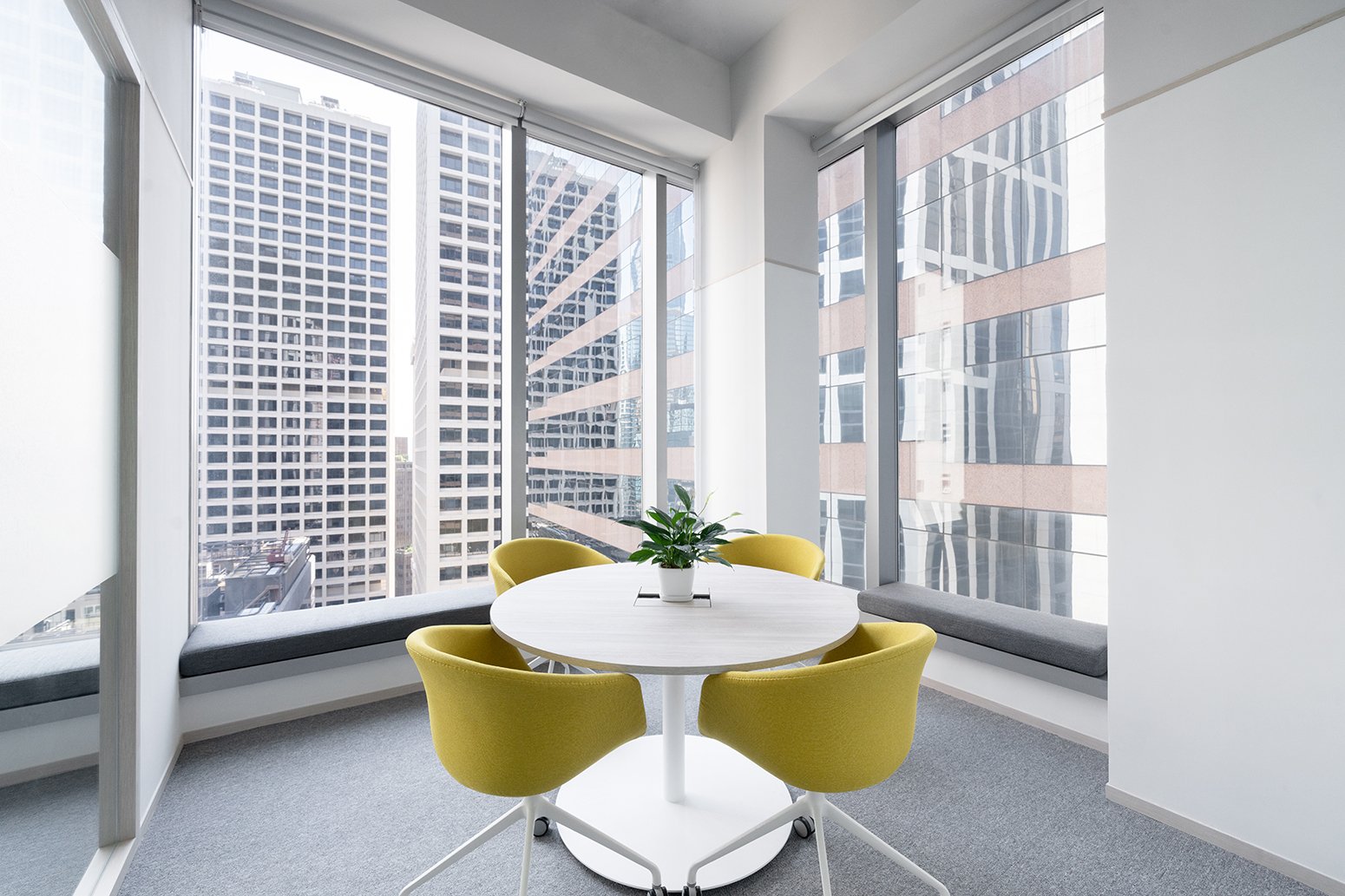 Panthevm Partners office by Wan Fang Construction showing a round white table, yellow chairs & green plants for a bright, collaborative workspace in Hong Kong, Central.
