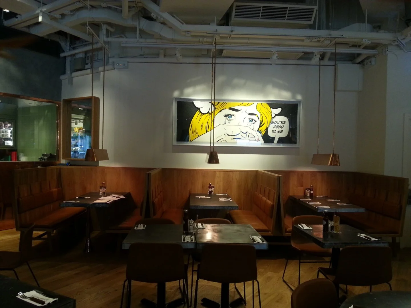 Beef & Liberty, a gourmet burger restaurant in Stanley Hong Kong by Wang Fang Construction, features a modern interior. The space has an exposed ceiling with recessed lighting and fans over polished hardwood floors. Long communal tables with leather 