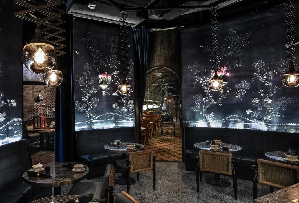 Mott 32, an award-winning Chinese Restaurant, interior dining area by Wang Fang Construction, featuring dark tables set for dining, and a mix of modern and rustic decor, and large windows engraved with flowers in Hong Kong Central.
