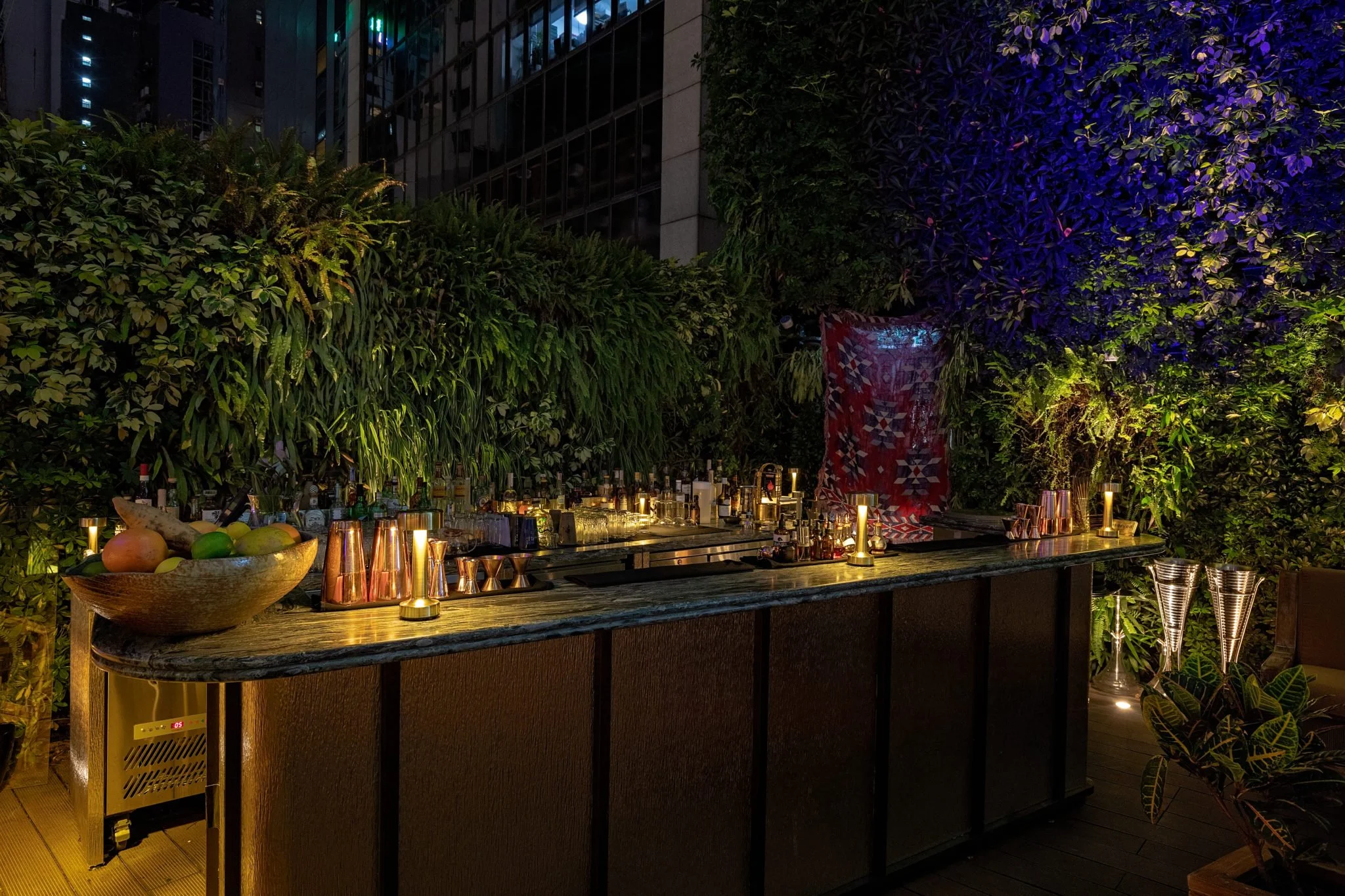 ICHU, an elegant restaurant and rooftop terrace by Wan Fang Construction, a modern rooftop terrace featuring bar counter in the vibrant vertical garden of purple and green foliage that creates a striking backdrop. Contemporary, neutral-toned furnitur