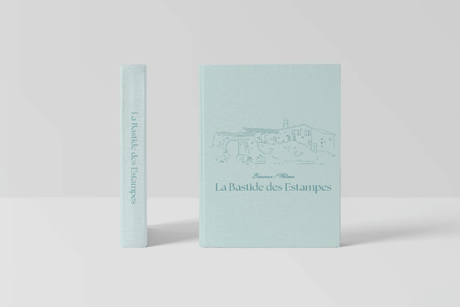Couverture et dos d'un livre intitulé 'La Bastide des Estampes', avec une illustration d'une bâtisse ancienne et un paysage rural en lignes fines, en couleur bleue pastel.