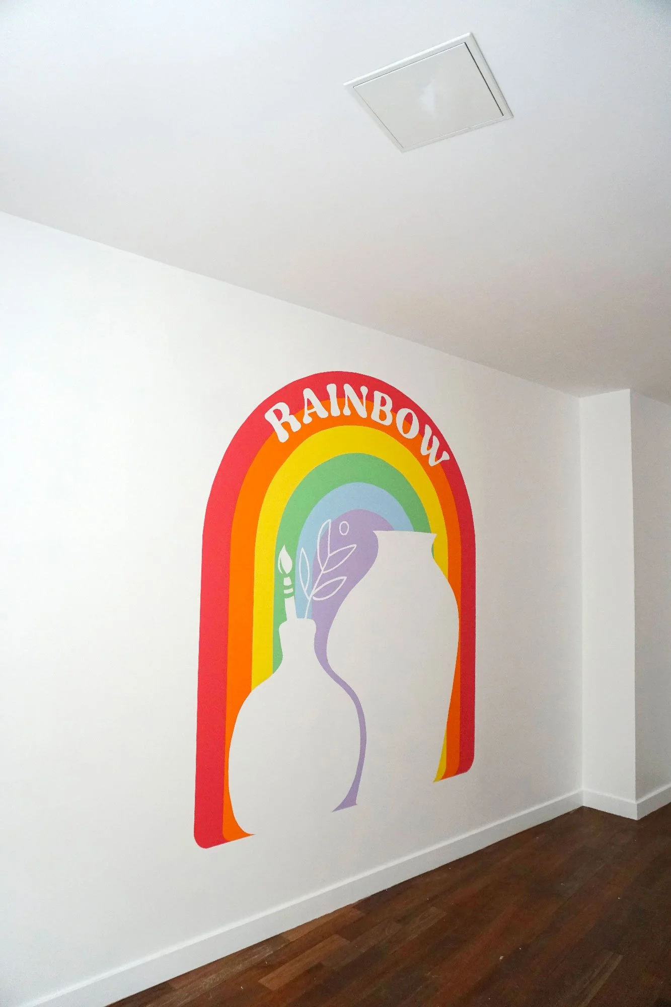 Mural coloré représentant l'arc-en-ciel avec le mot 'RAINBOW' en haut, peinture d'un logo arc-en-ciel