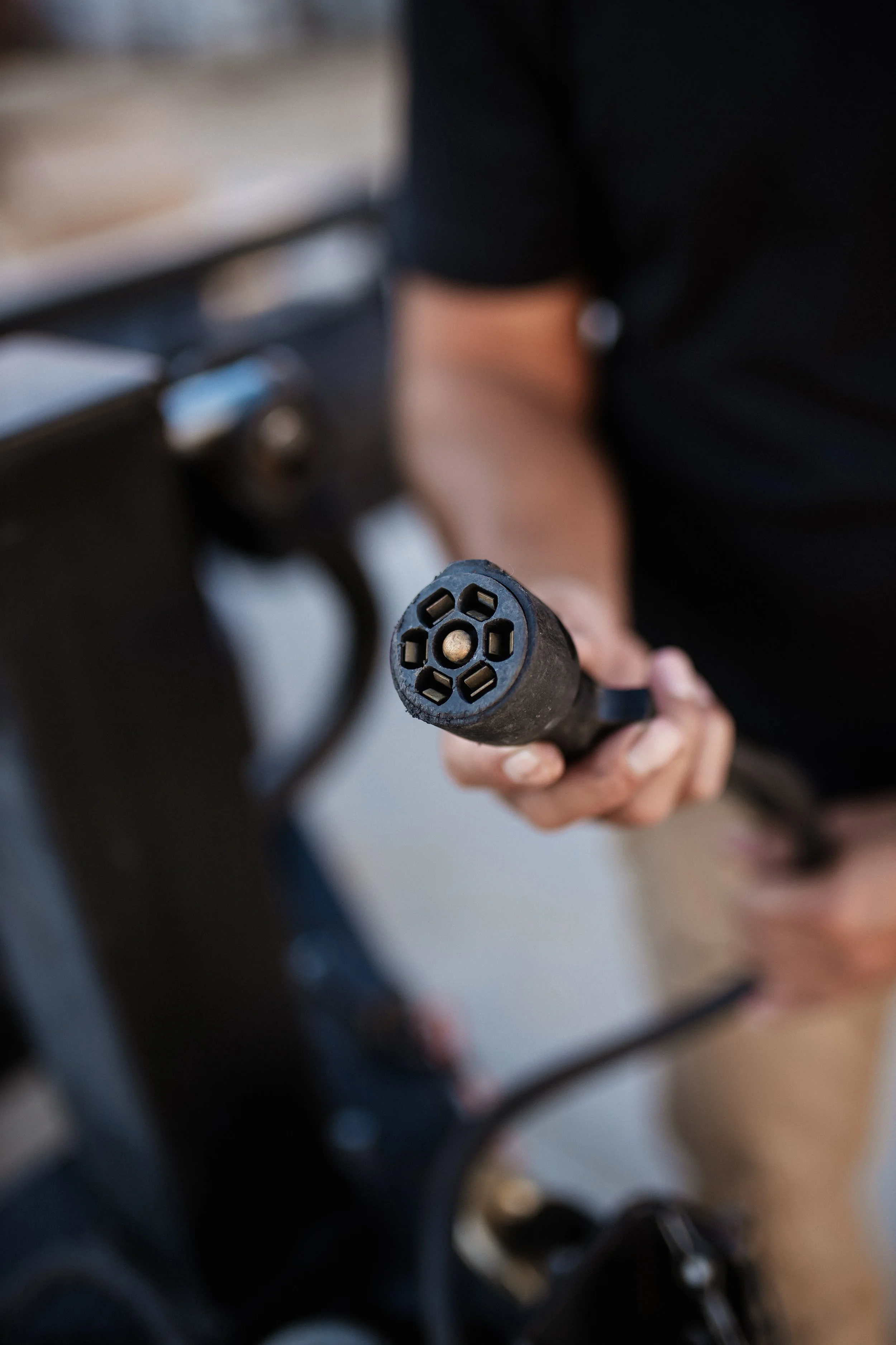 A person holding a black power tool with a circular connector at the end.