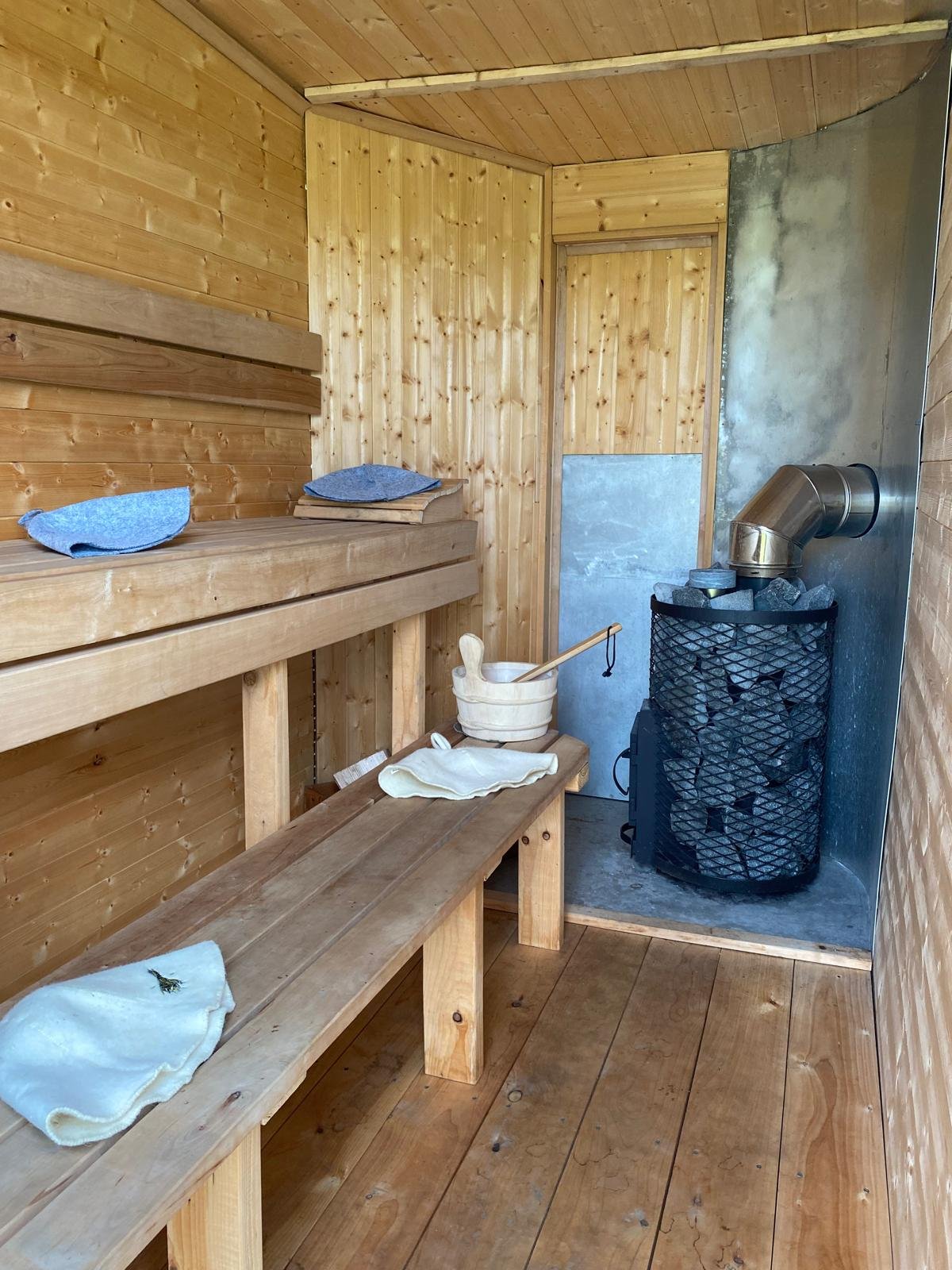 Wood-paneled sauna room and a sauna stove filled with rocks at Hot Rocks Sauna
