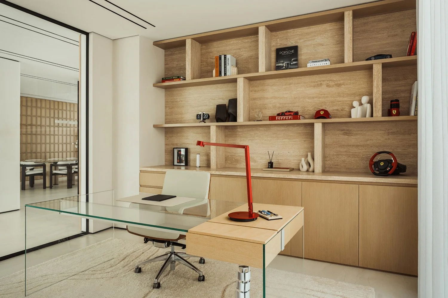 Home office in Villa Ambra, Dubai, with custom ivory travertine shelving, oak cabinetry and a glass desk.