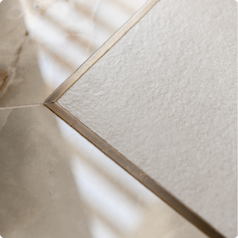 Limestone signature detail — marble strip framing wooden flooring at windows, terminated with brushed brass metal trim for moisture and sun protection, luxury interior design Dubai