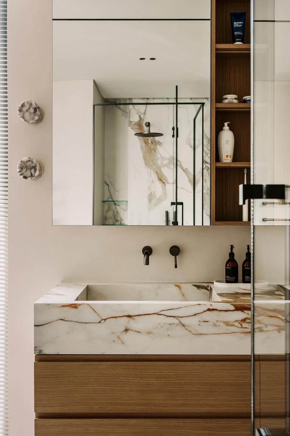 Luxury bathroom vanity with Calacatta marble countertop, integrated sink, oak cabinetry, matte black wall-mounted tapware, and stone cabinet pulls by Limestone