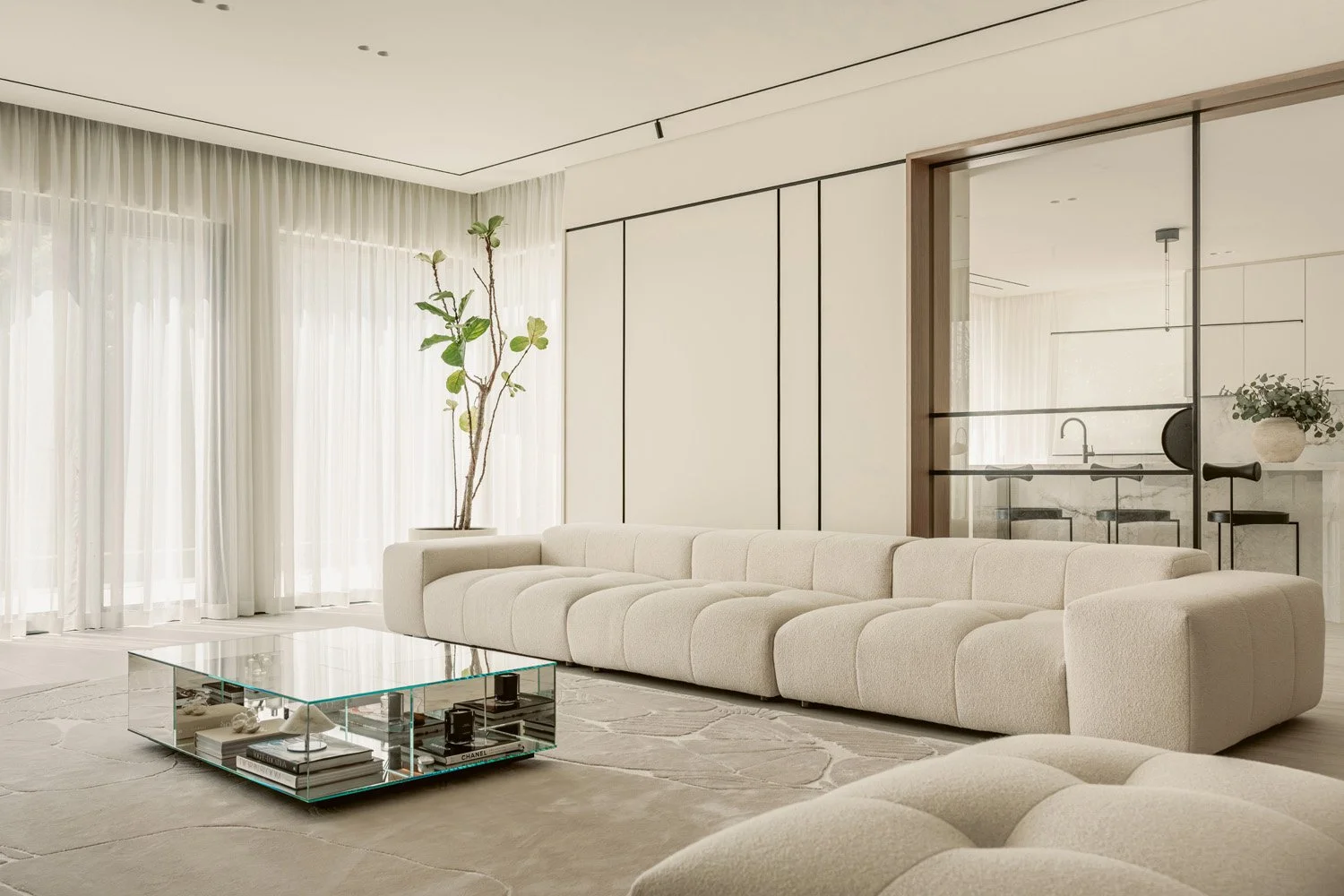 Expansive all-white luxury living room with a tufted bouclé sectional sofa, mirrored glass coffee table, floor-to-ceiling sheer drapes, and panelled wall joinery, Aurora villa designed by Limestone in Dubai