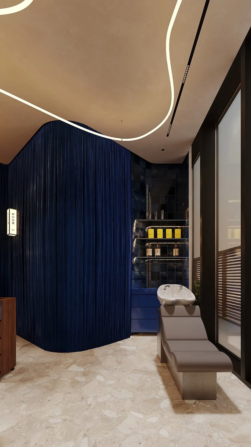 Hair wash area at FŌM Hygge Spa, City Walk Dubai, by Limestone, with a reclining basin, curved pleated blue velvet wall and backlit Zellige retail shelving