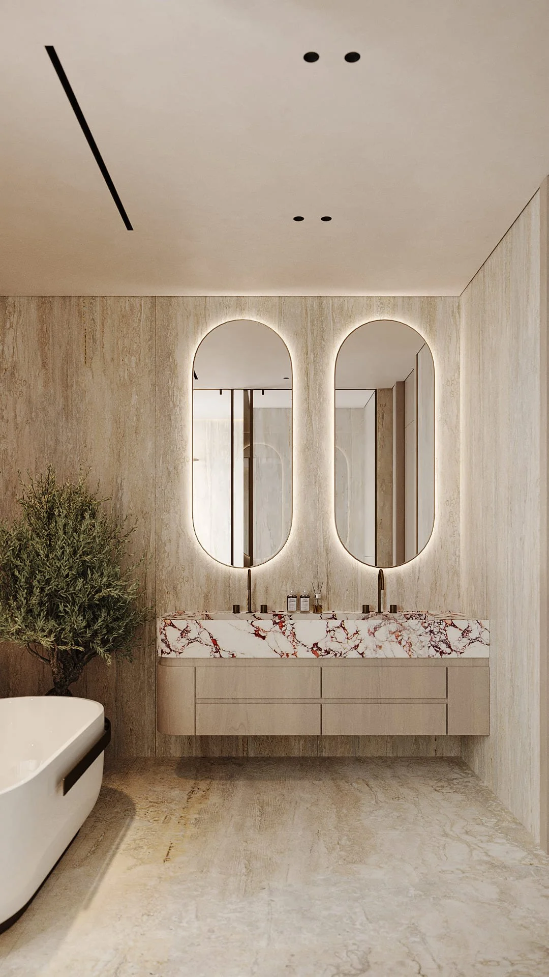 Master bathroom double vanity in Villa De Bomma, Jumeirah Islands, with Calacatta Viola marble countertop, travertine wall cladding, two backlit oval mirrors, and an olive tree by Limestone