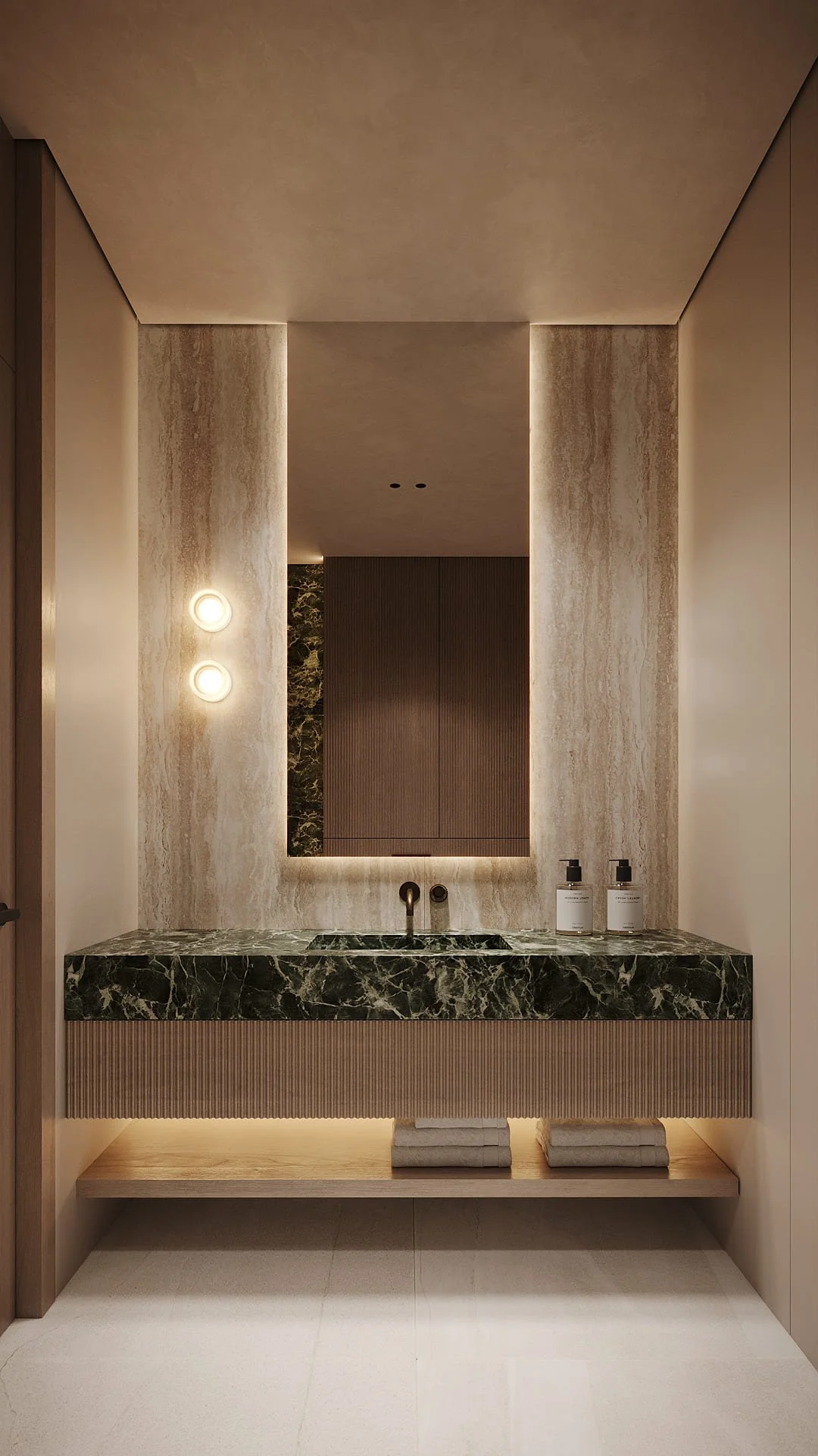 Bathroom vanity in Villa De Bomma, Jumeirah Islands, featuring an Alpi Verde marble countertop, travertine wall panels, and backlit mirror by Limestone