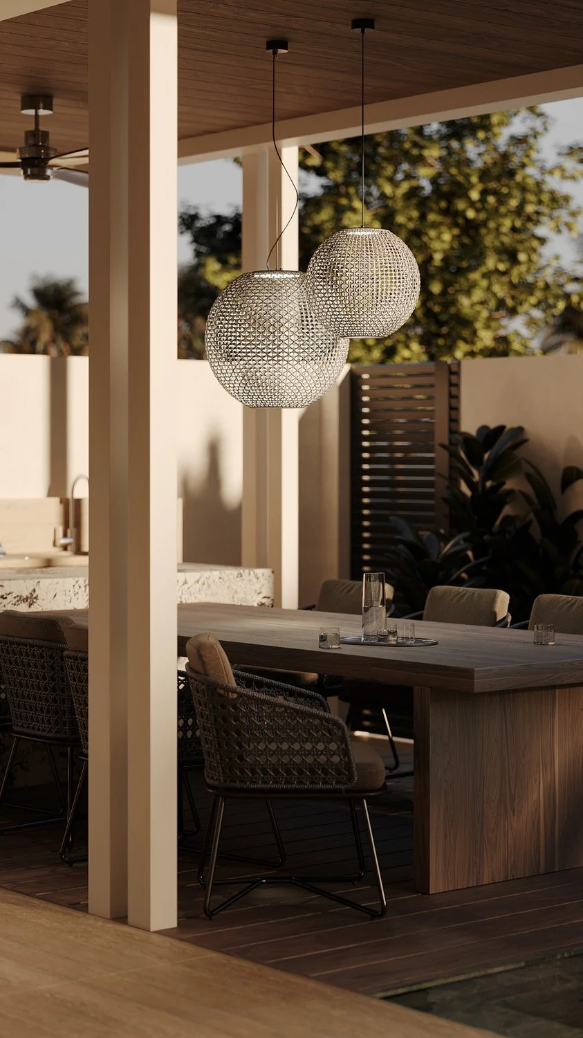 Detail of woven pendant lighting above the outdoor dining table in a Dubai Hills villa landscape, with a wood dining table and rattan chairs, designed by Limestone