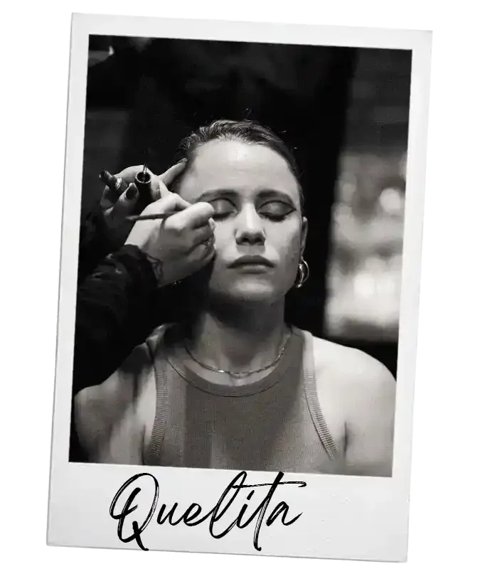 Zwarte en witte foto van een vrouw huisgemaakt, ze krijgt make-up. Op de foto staat de tekst 'Queltita'.