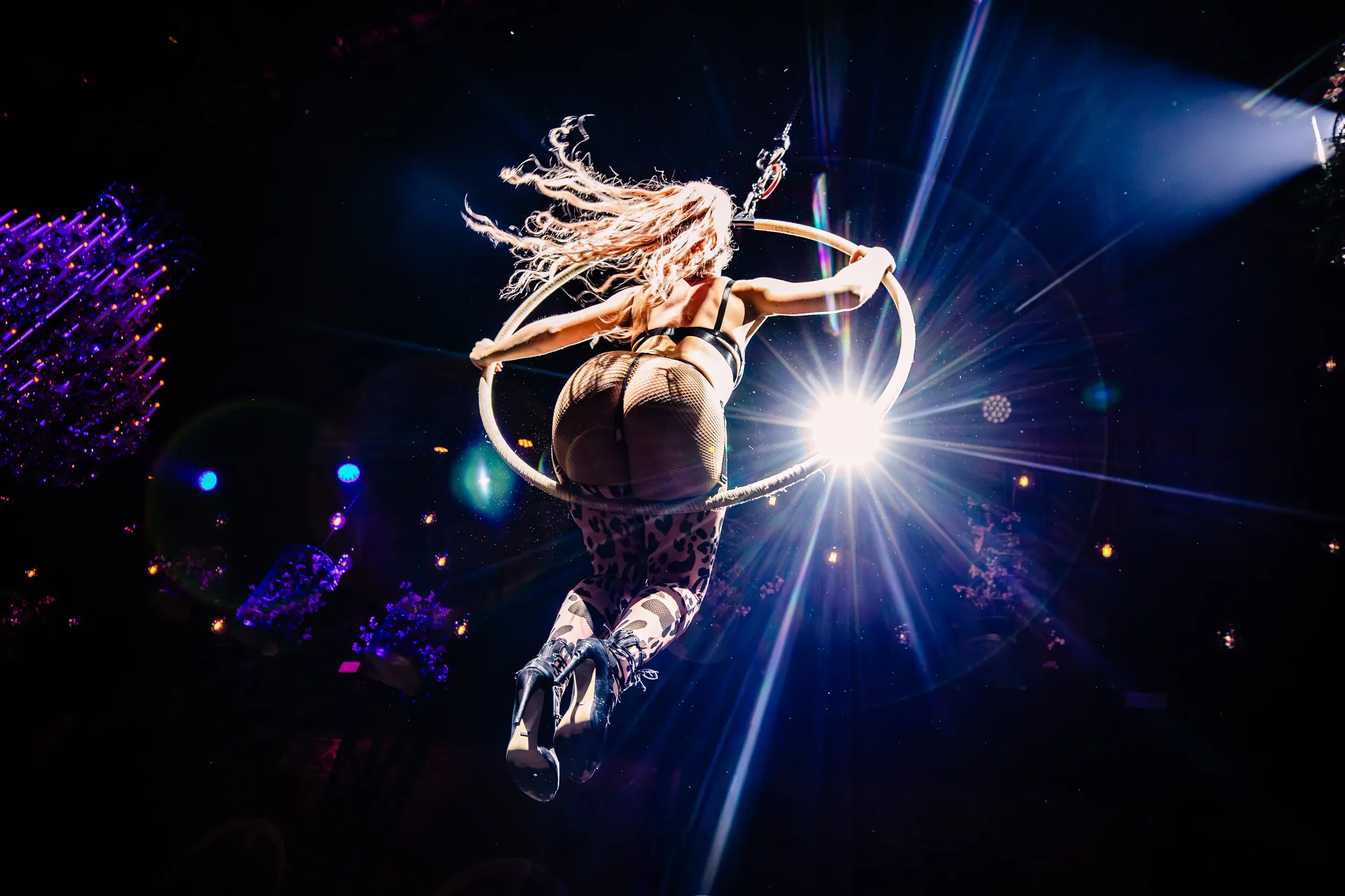 Een vrouw die cirkelvormig in een circusring op een podium springt, met professionele verlichting en een donkere achtergrond.