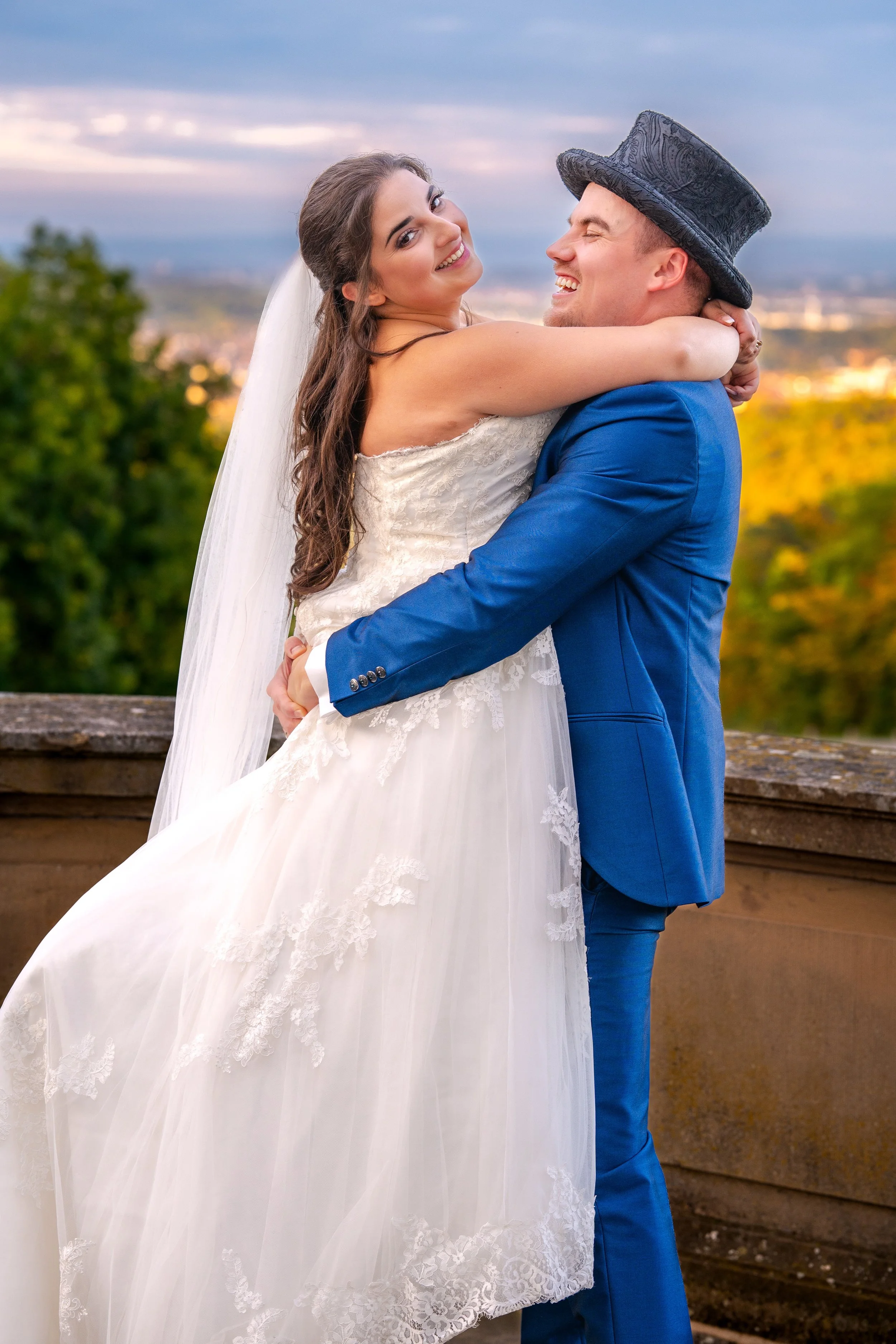 Ein glückliches Brautpaar, das sich umarmt, bei Sonnenuntergang im Freien.