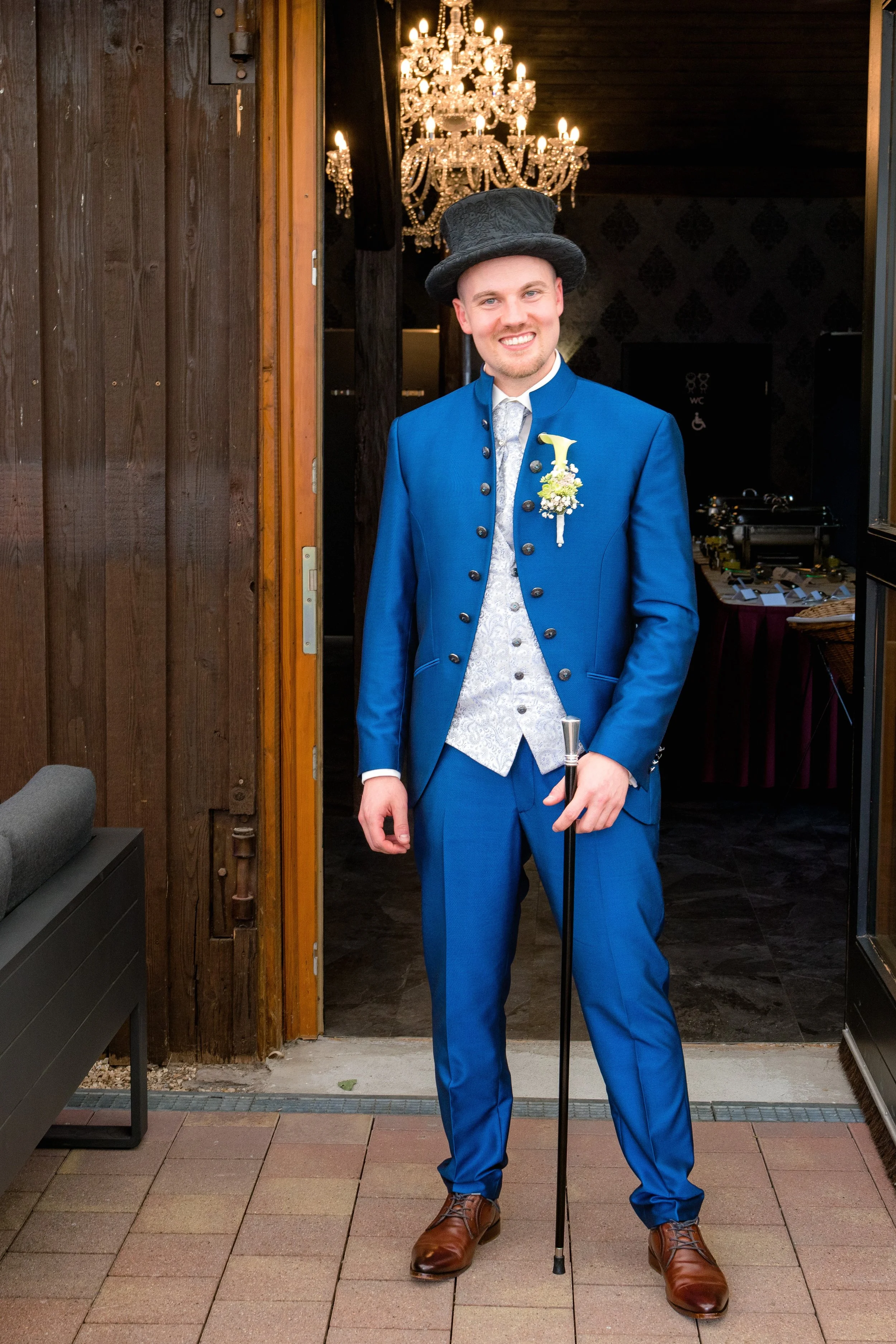 Der Bräutigam wartet in der Location Hofgut Domäne in Hechingen auf seine Gäste. Er trägt einen blauen Anzug und lächelt.  