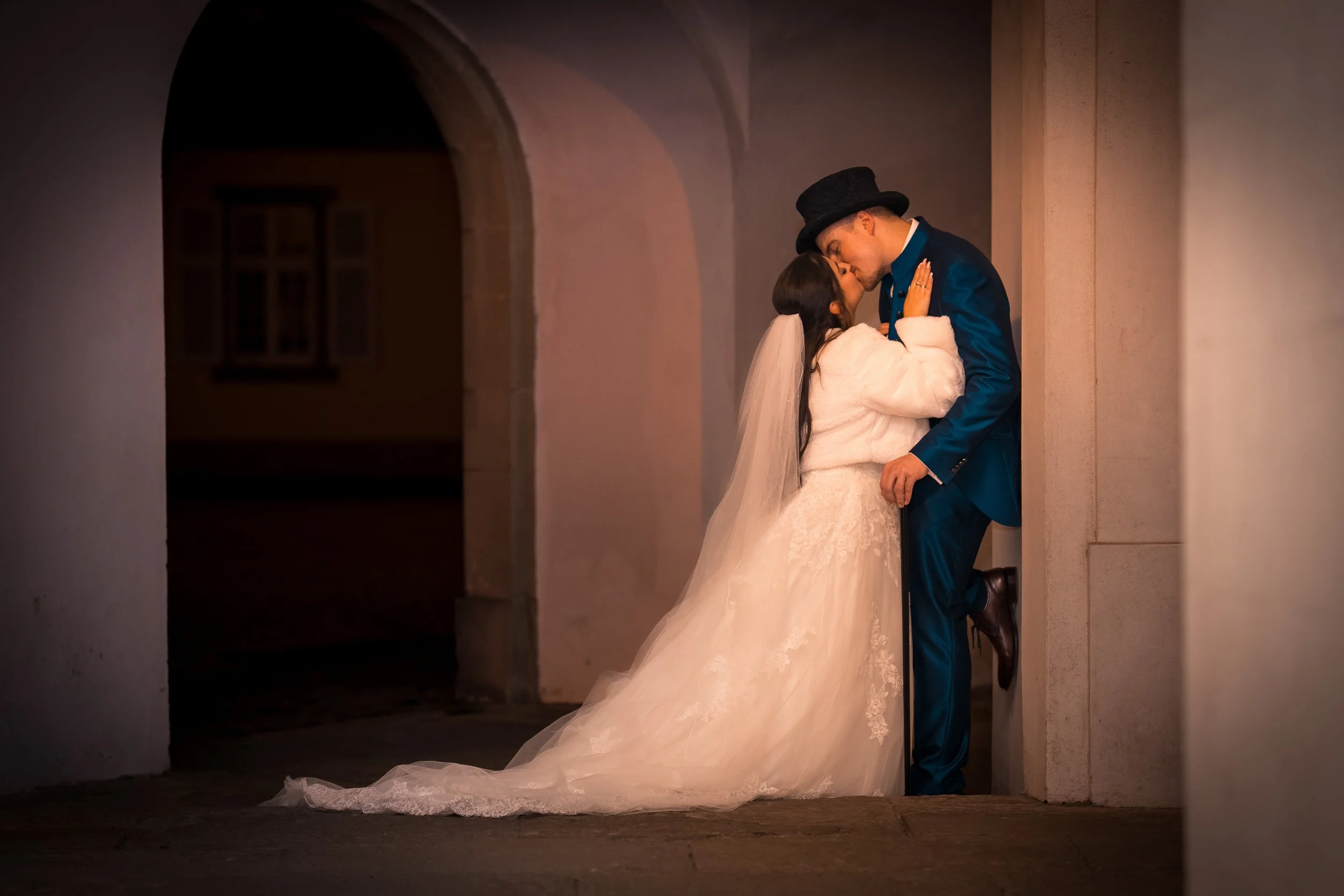Ein Brautpaar in Hochzeitskleidung teilt einen Kuss in einer romantischen Abendaufnahme in einem Tunnel.