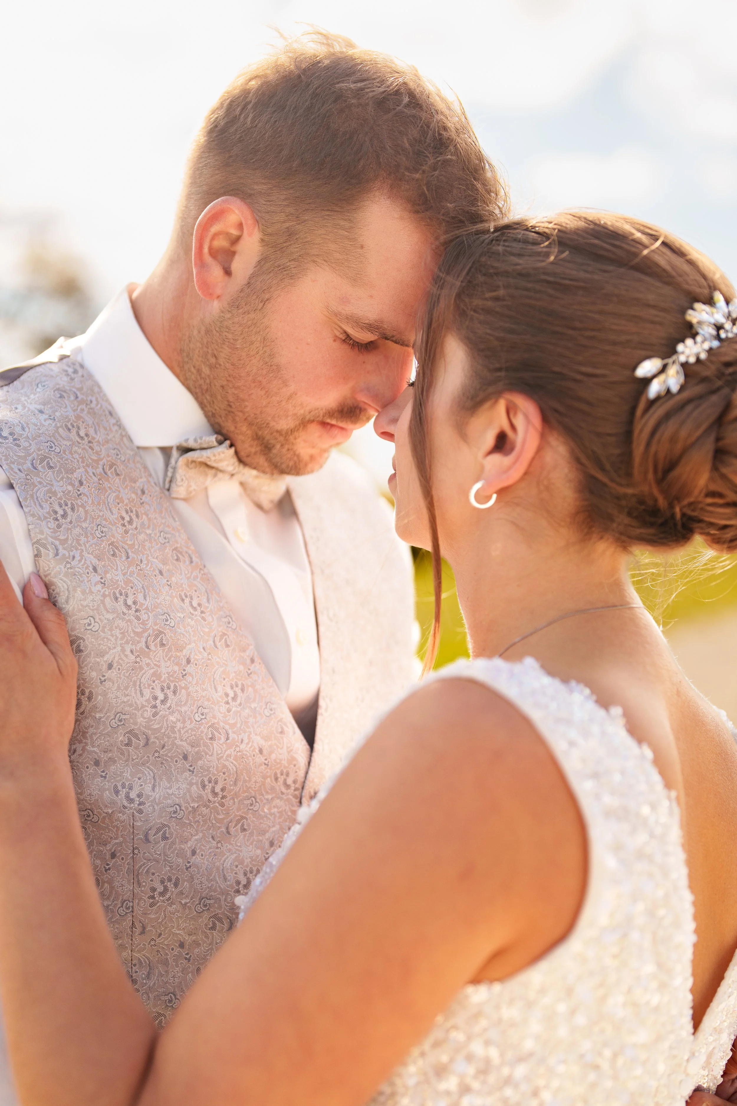 Ein verliebtes Paar bei einer Hochzeitszeremonie, mit den Köpfen aneinander, im Sonnenschein.
