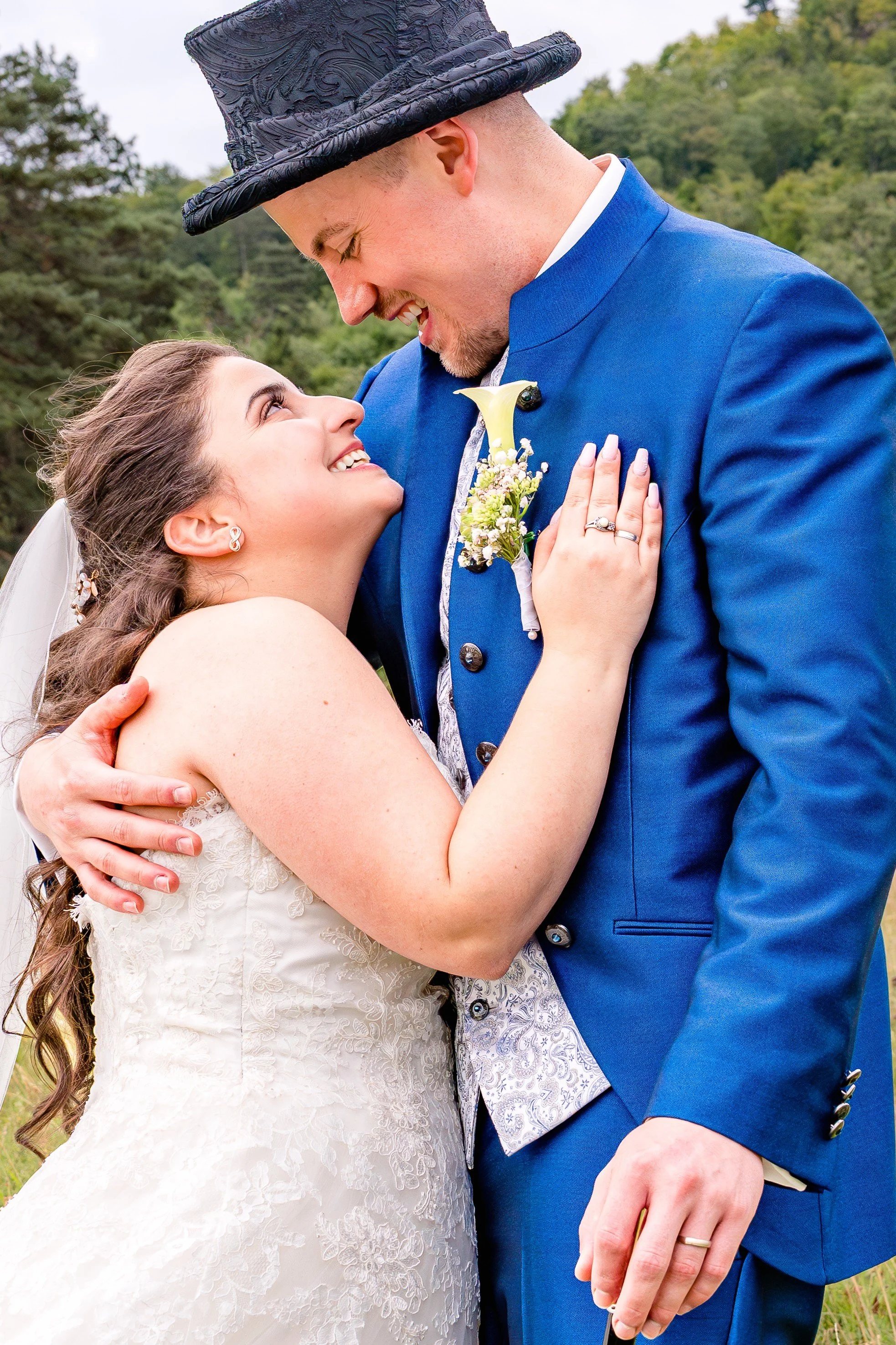 Eine Nahaufnahme eines Brautpaares, das sich liebevoll in den Armen hält und sich anschaut. Beide lächeln sich an. 