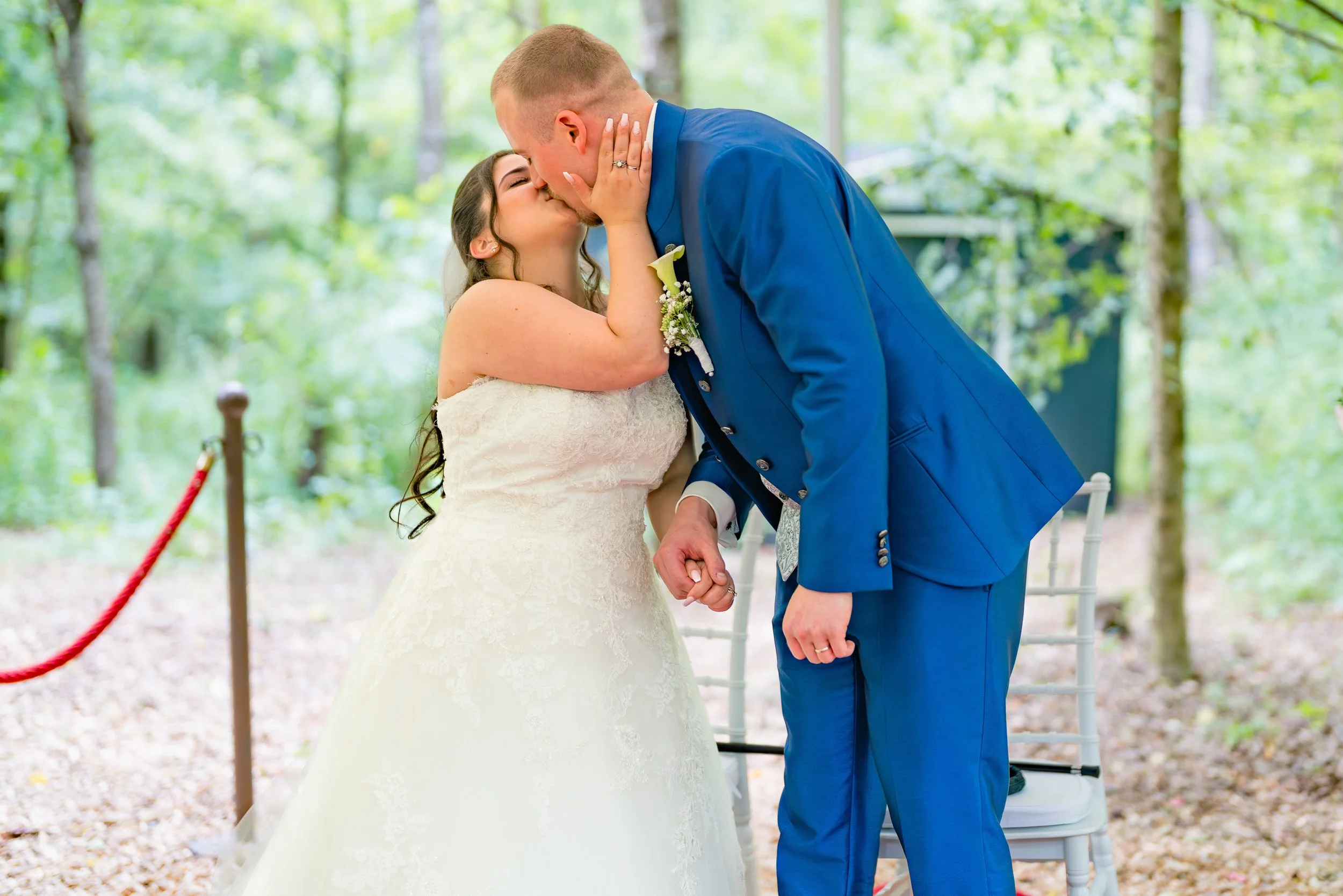 Ein Brautpaar küsst sich bei einer Hochzeit im Freien.