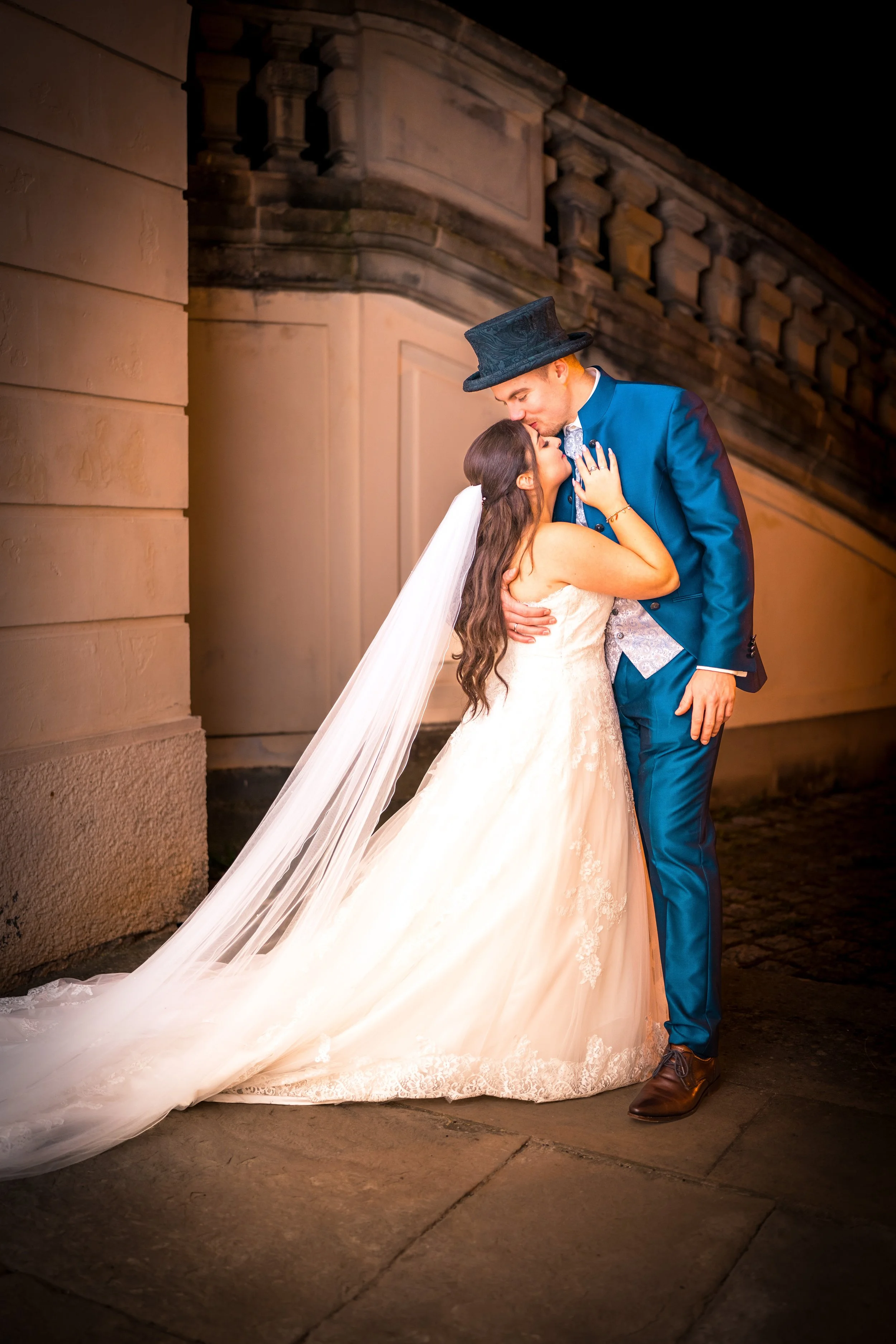 Braut und Bräutigam küssen sich bei Nacht vor einem Gebäude