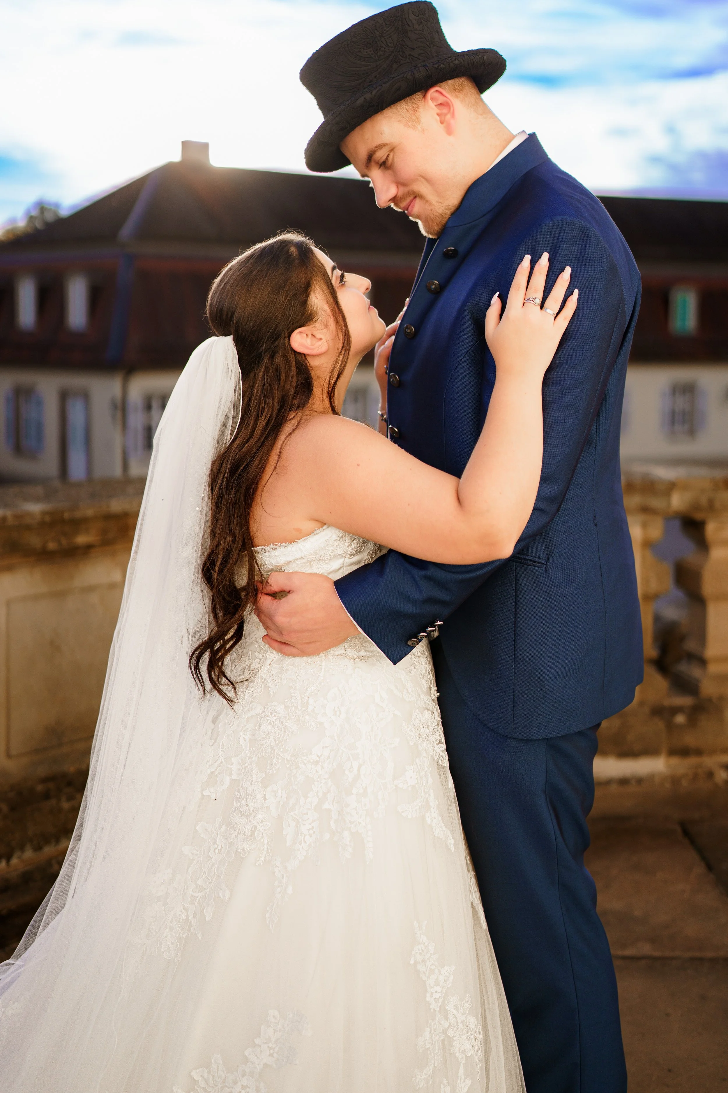 Braut und Bräutigam umarmen sich bei Sonnenuntergang auf einem Balkon.