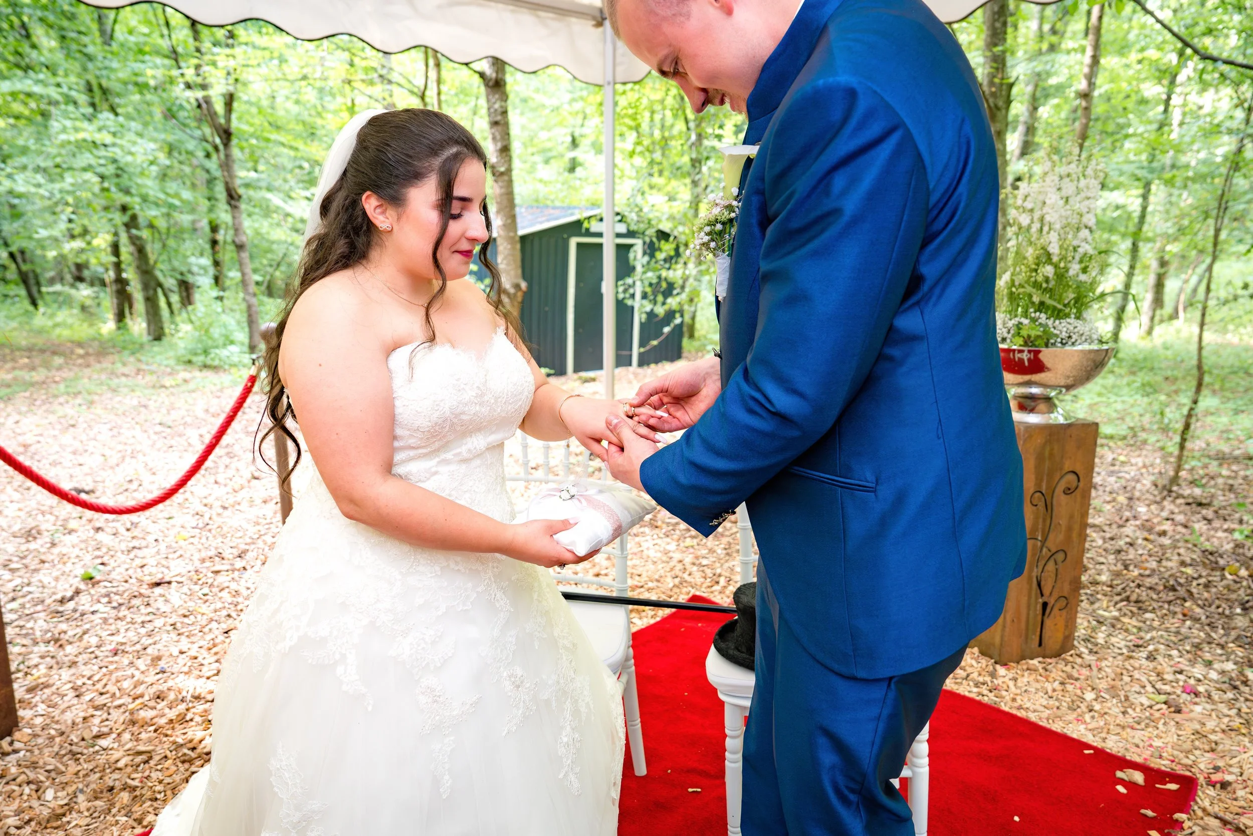 Ein Brautpaar bei einer standesamtlichen Trauung im Freien, der Bräutigam legt den Ehering an die Braut.