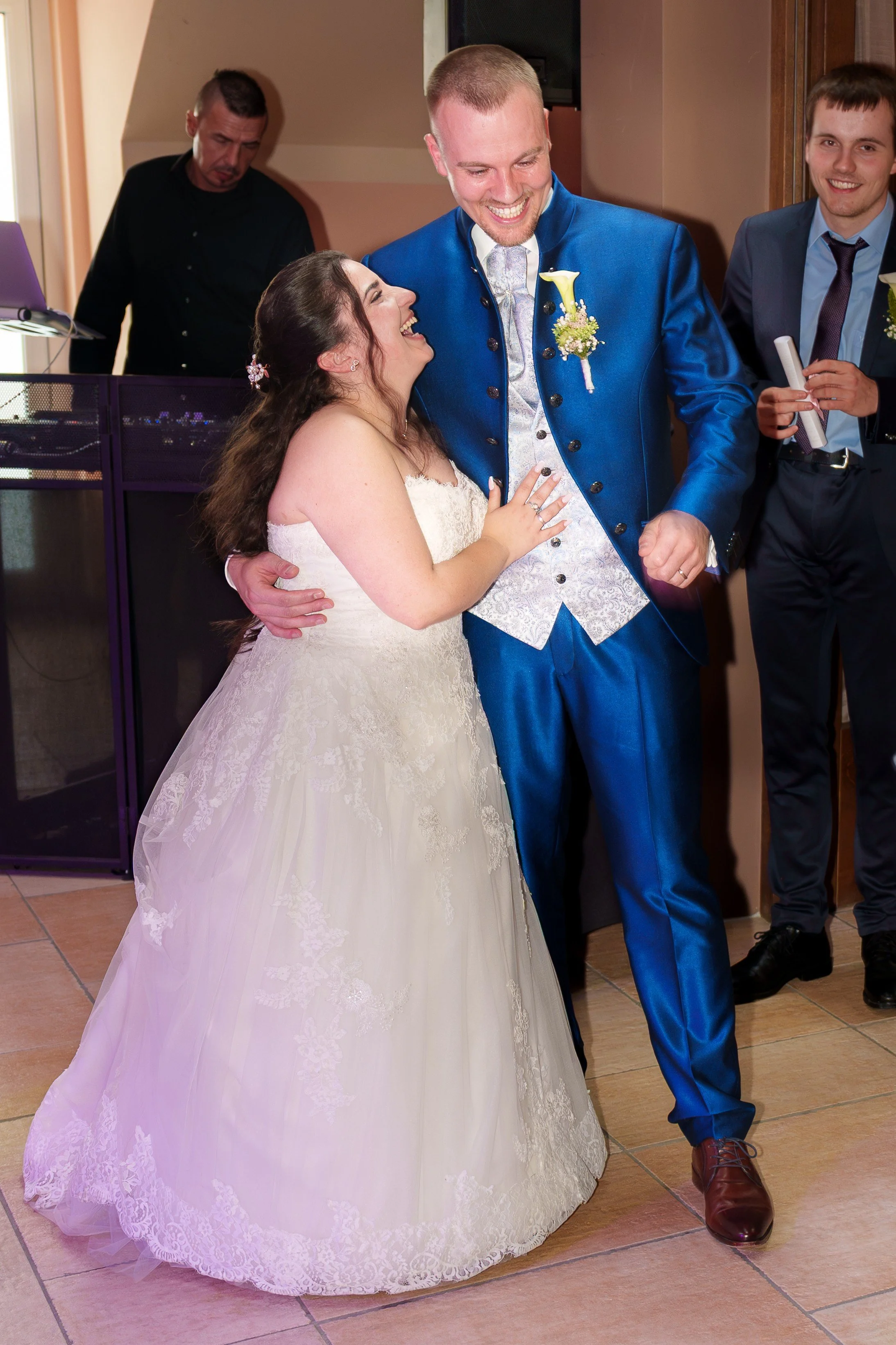 Braut und Bräutigam tanzen bei ihrer Hochzeit, lachen und genießen den Moment, umgeben von Freunden und Familie.