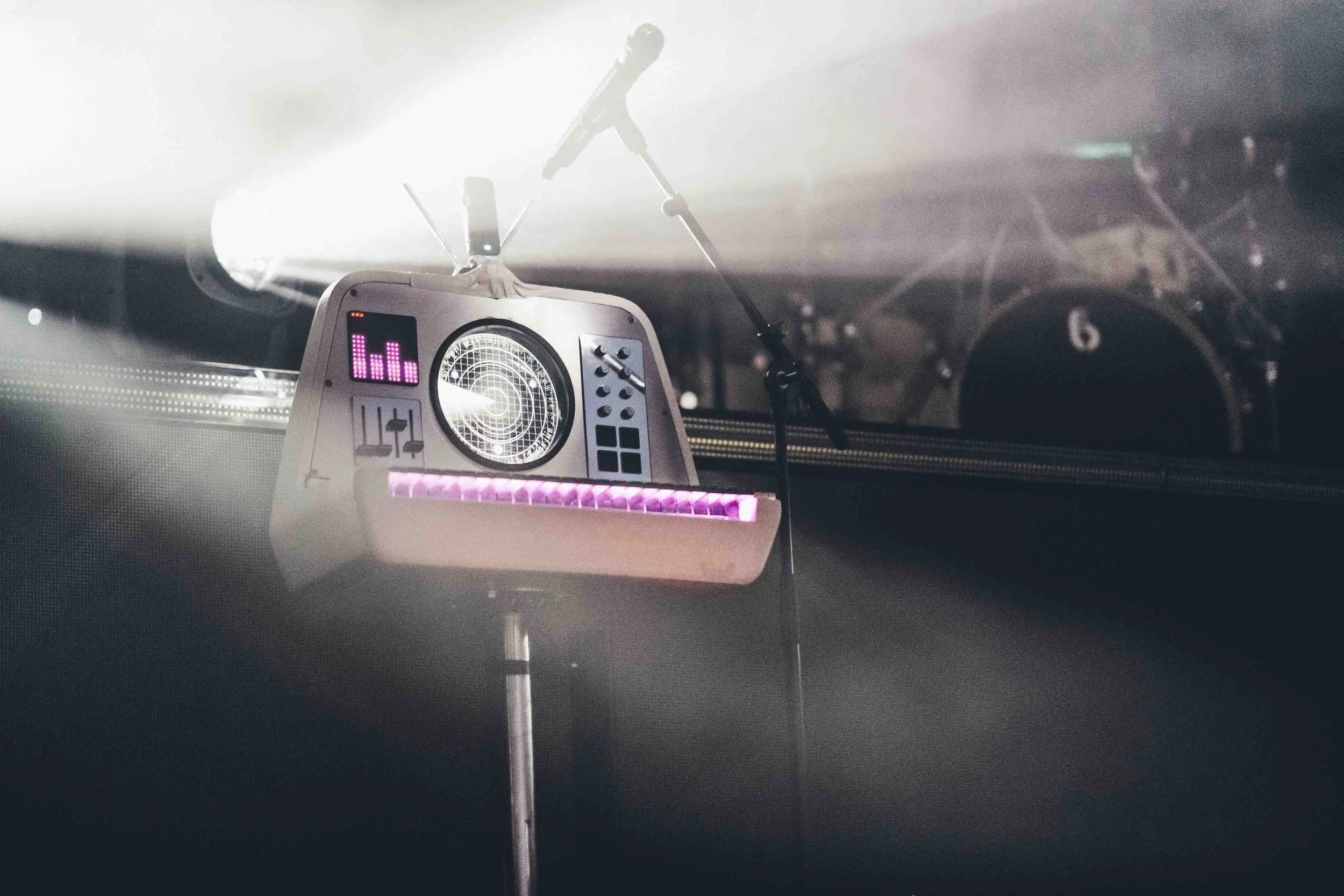 A close-up of a DJ's electronic music mixer (Sparky of Enter Shikari) with lights and gauges, set on a stand in a dark environment.