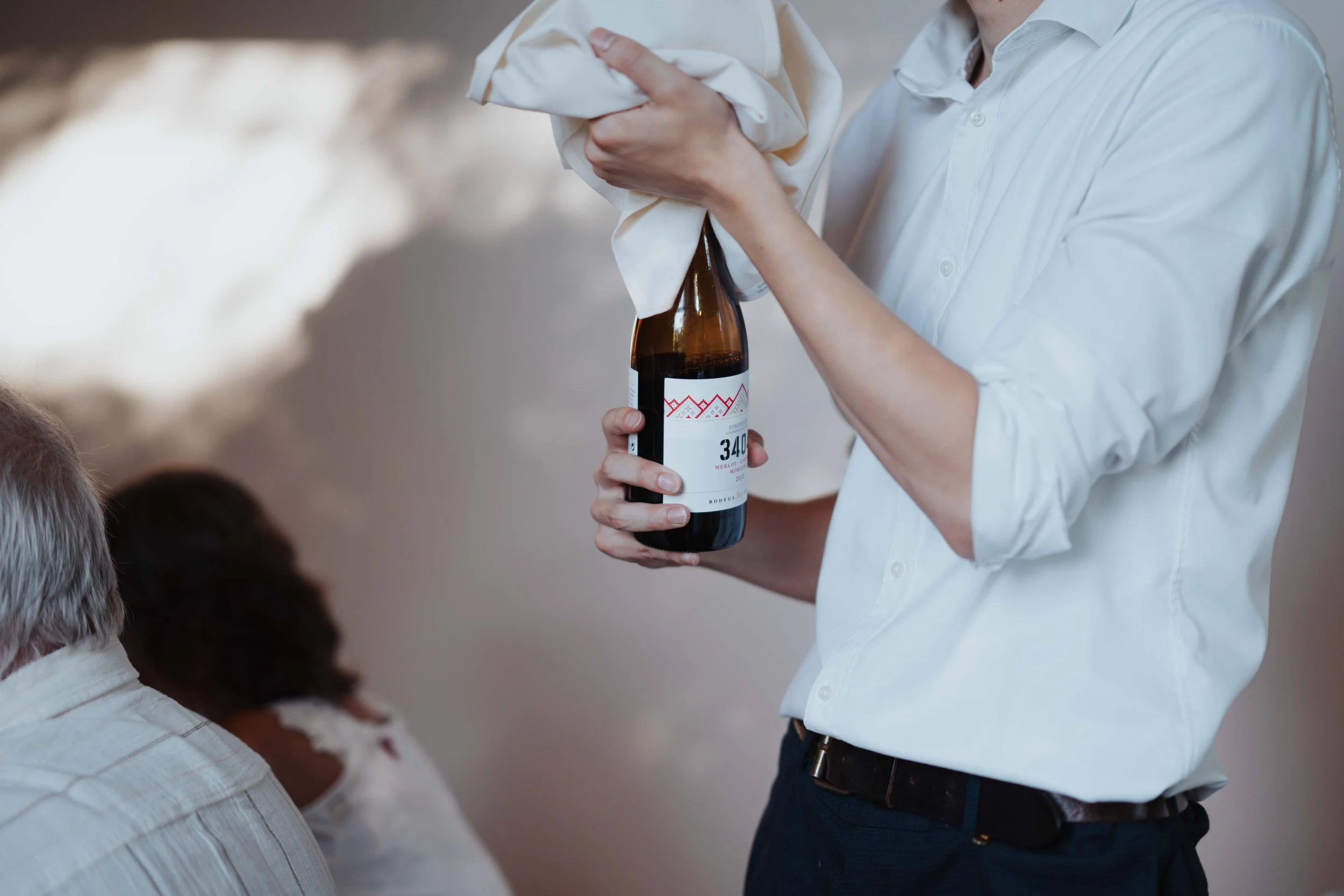 Person opening a bottle of wine during a social gathering.
