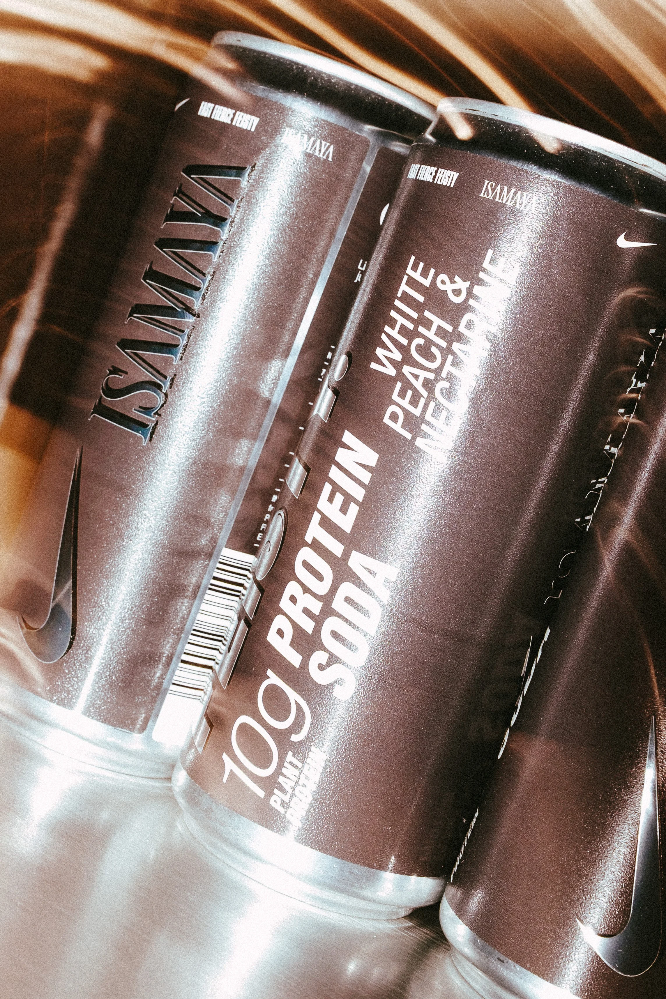 Close-up of dark brown containers of protein powder labeled '10g Protein Purity' and 'Plant-Based Protein' on a silver metallic surface.