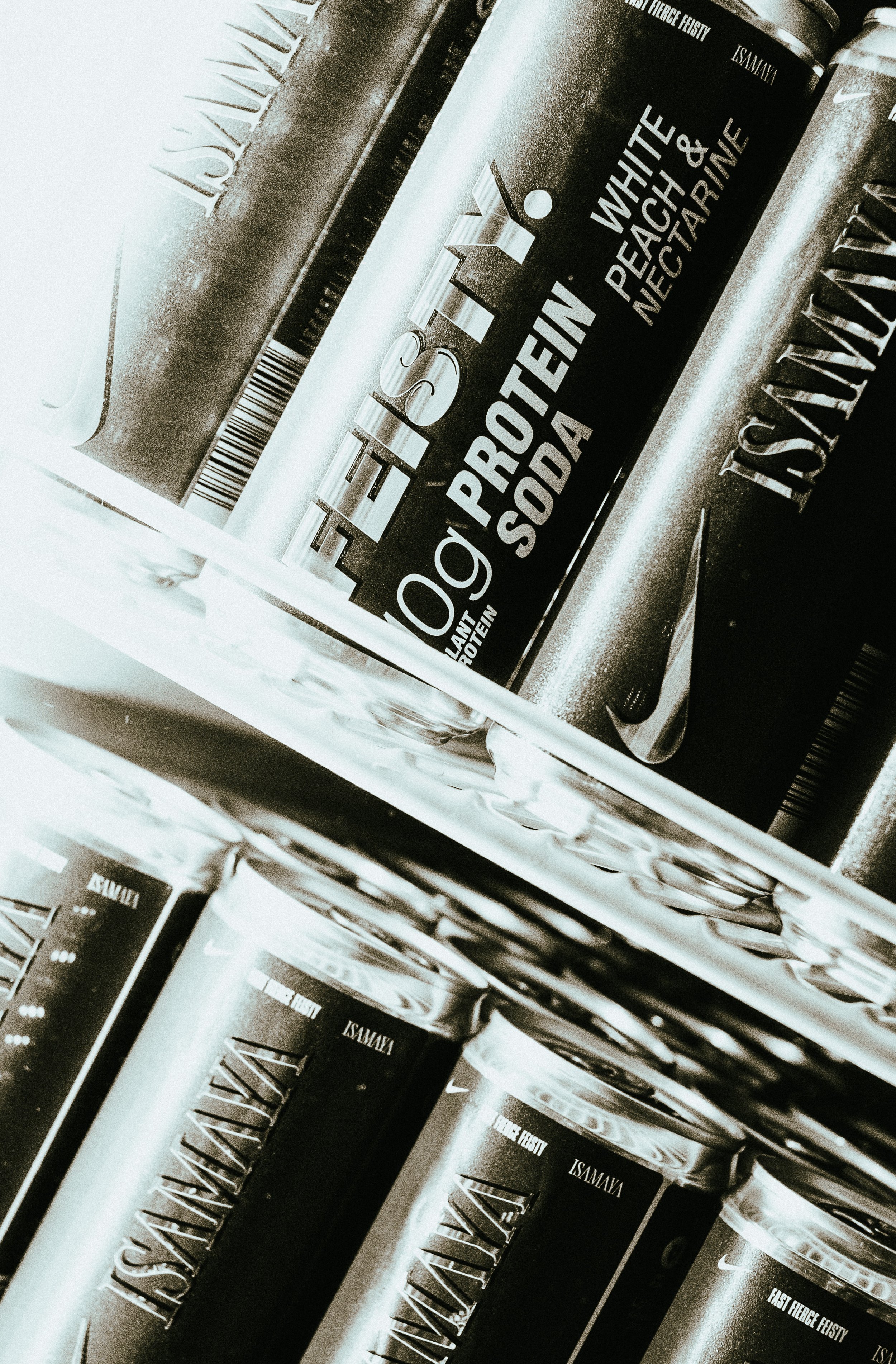 Shelf of protein workout supplement containers with black and silver labels, including flavors like last fierce fiesty and neutron, on a supermarket store shelf.