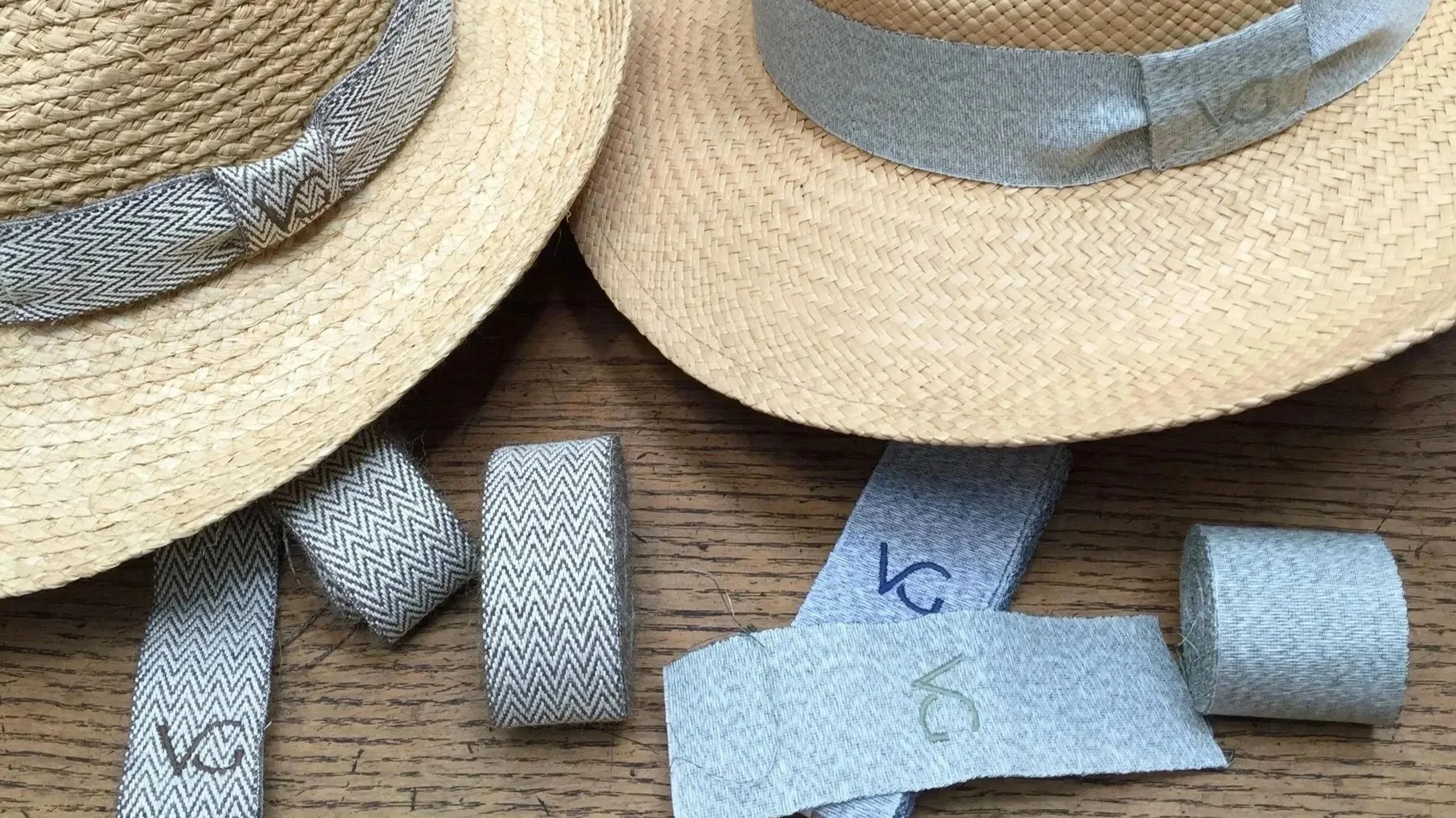Chapeaux en paille, certains avec bandes en tissu, posés sur une surface en bois.