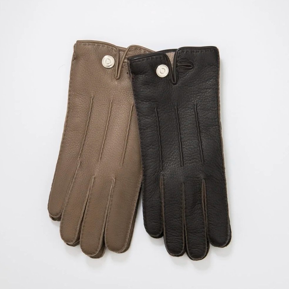 Deux paires de gants en cuir, une beiges et une noires, posées l'une sur l'autre sur fond blanc.