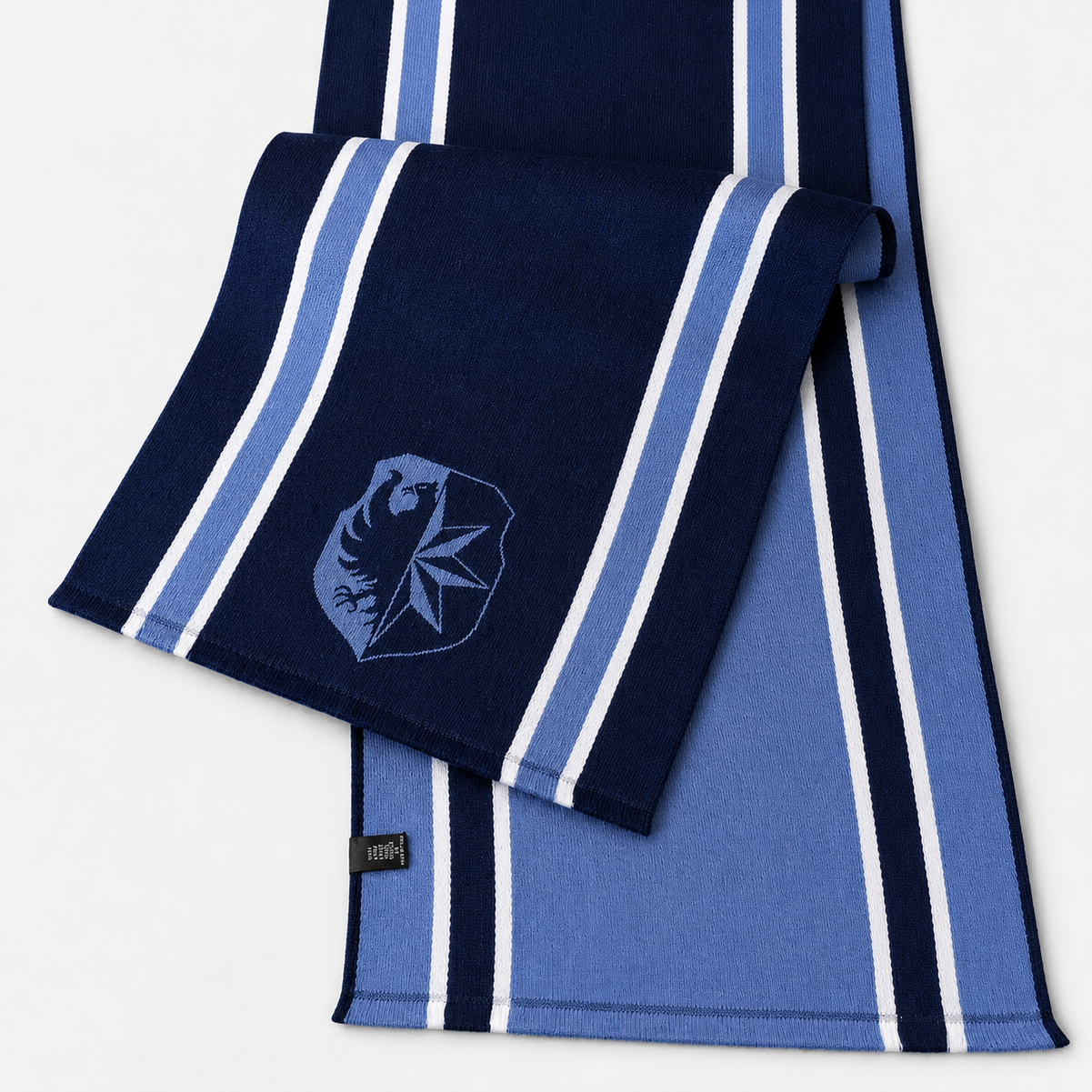Une écharpe rayée bleu clair, bleu foncé et blanc avec un logo bleu et noir représentant un ours et une feuille d'érable.