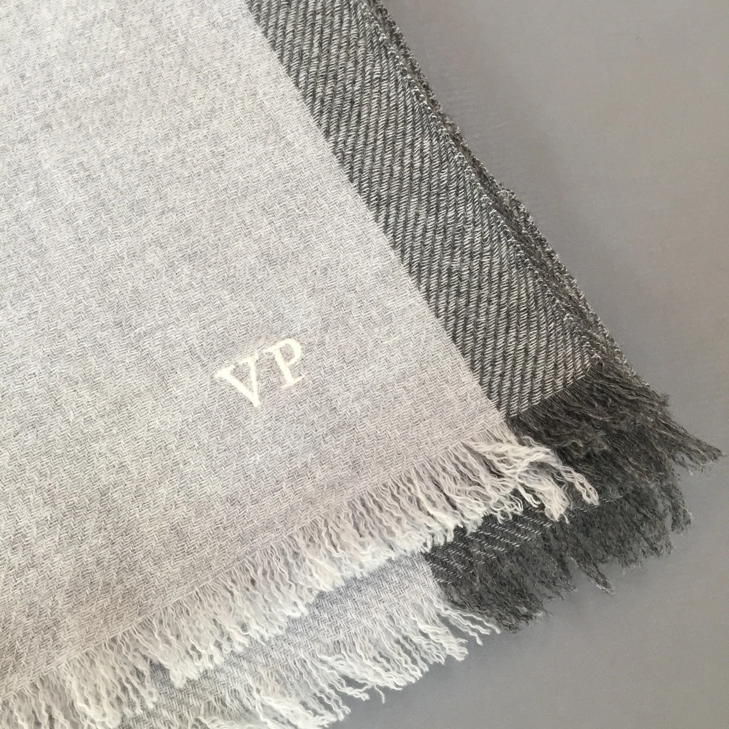 Photo d'un tissu en lin beige clair avec des franges blanches, posé sur un fond gris