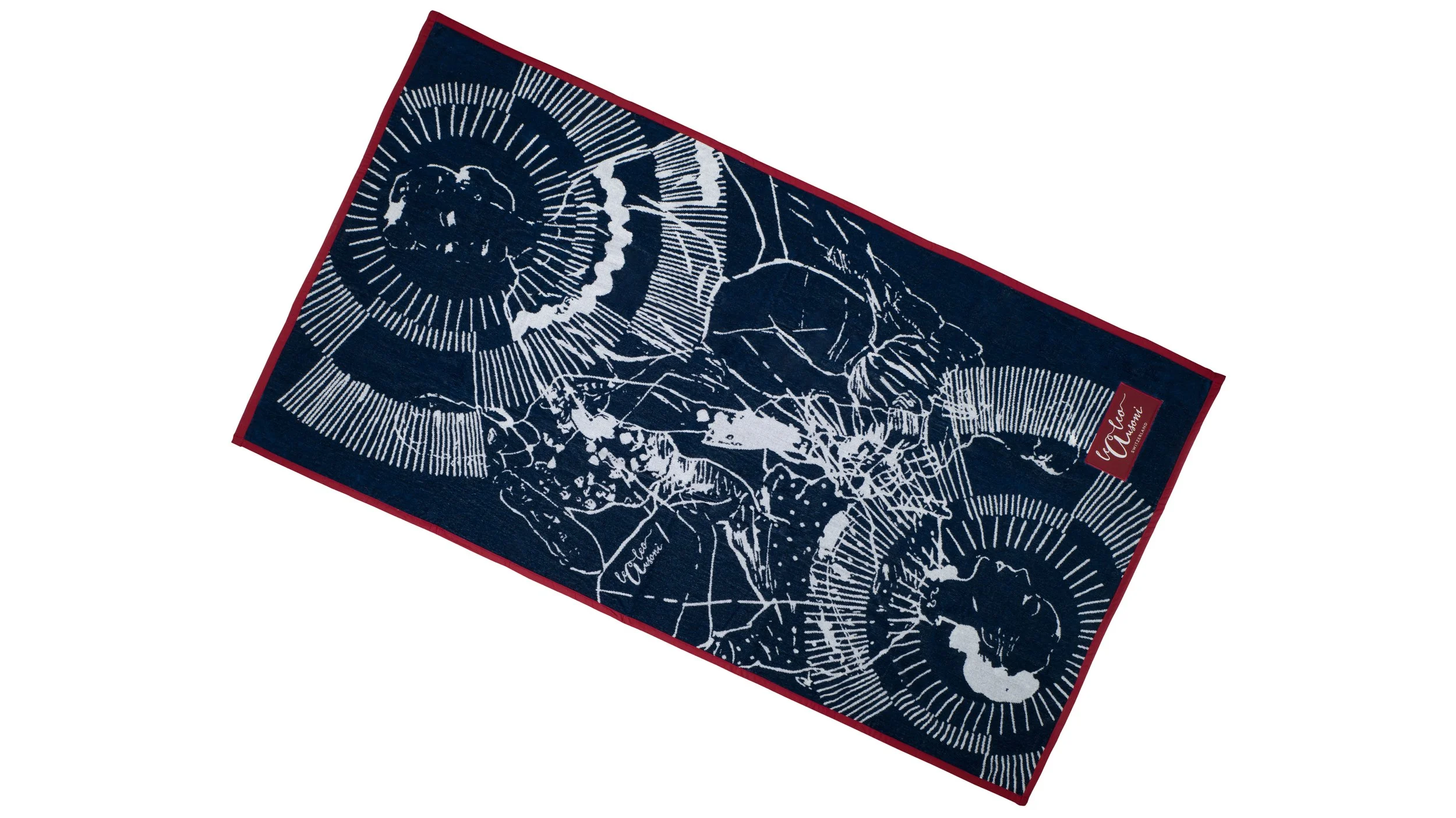 Un tapis de couleur bleu marine avec un motif blanc de lion et d'autres dessins, entouré d'une bordure rouge. En bas à droite, il y a une étiquette rouge avec le nom 'VIC MARQUE'.