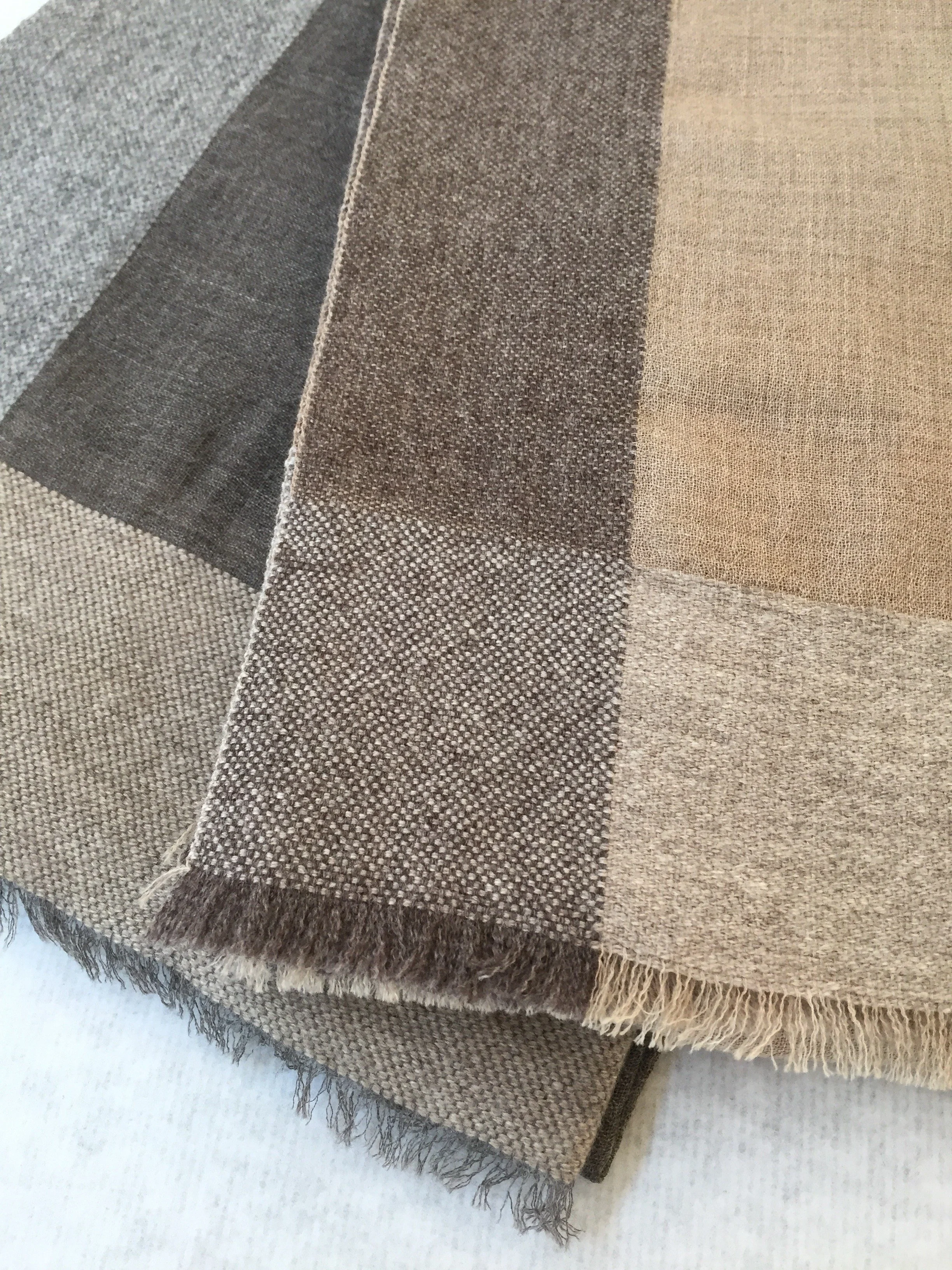 Couvrir en tissus beige, gris et marron avec des franges en bordure. Tissu en lin ou en coton avec différents motifs à carreaux et rayures.