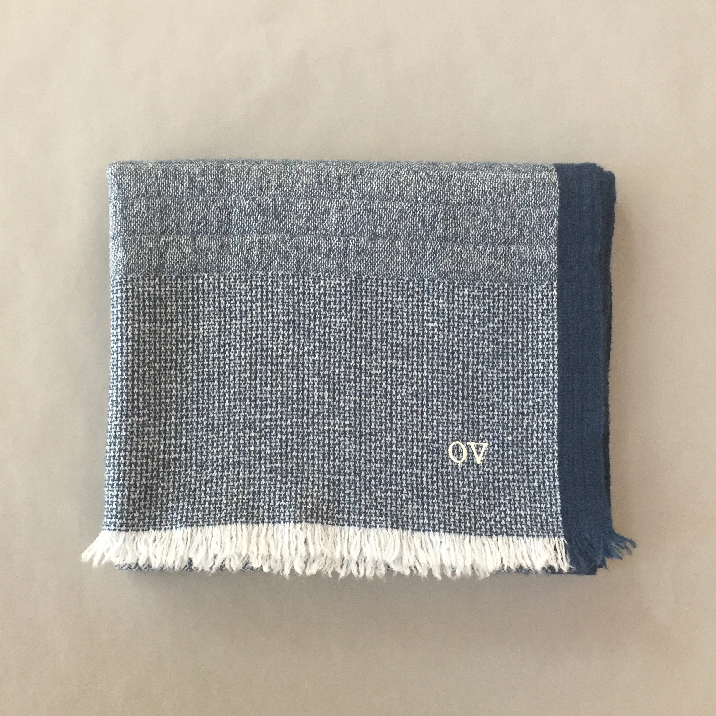 Une serviette de toilette en tissu gris et blanc avec un motif à rayures, posée sur une surface grainée