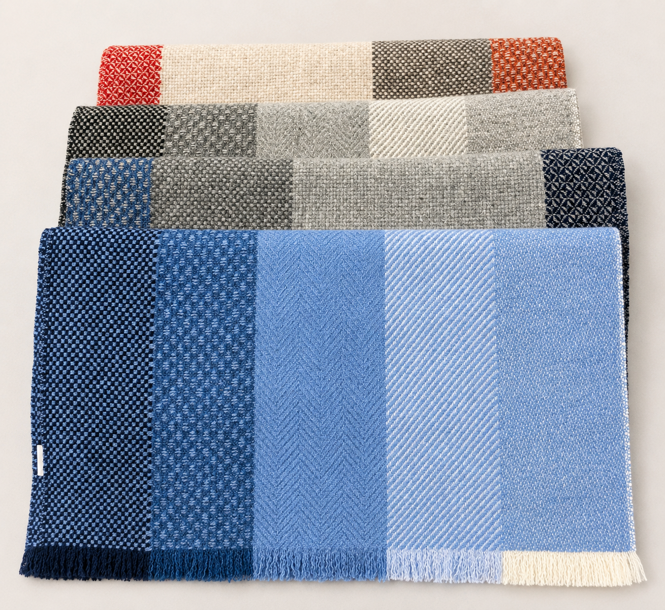 Quatre échantillons de tissus à motifs géométriques de différentes couleurs, du rouge au bleu en passant par le gris, disposés en rangées.