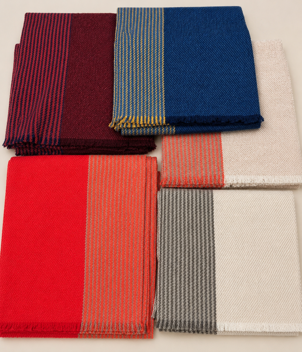 Six écharpes pliées de différentes couleurs et motifs sont disposées sur une surface blanche.