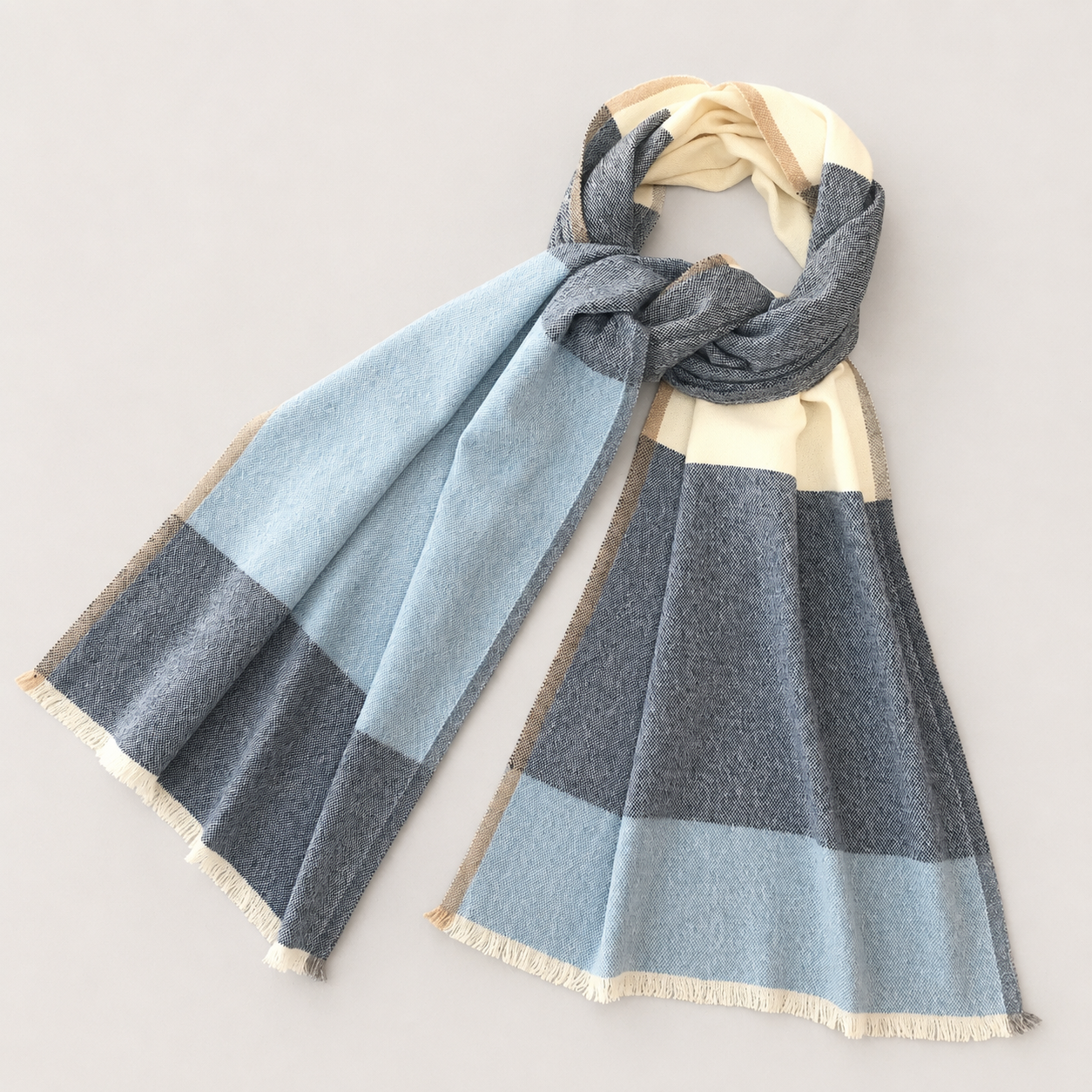 Écharpe à carreaux en nuances de bleu, gris, beige et crème, posée à plat sur fond blanc.