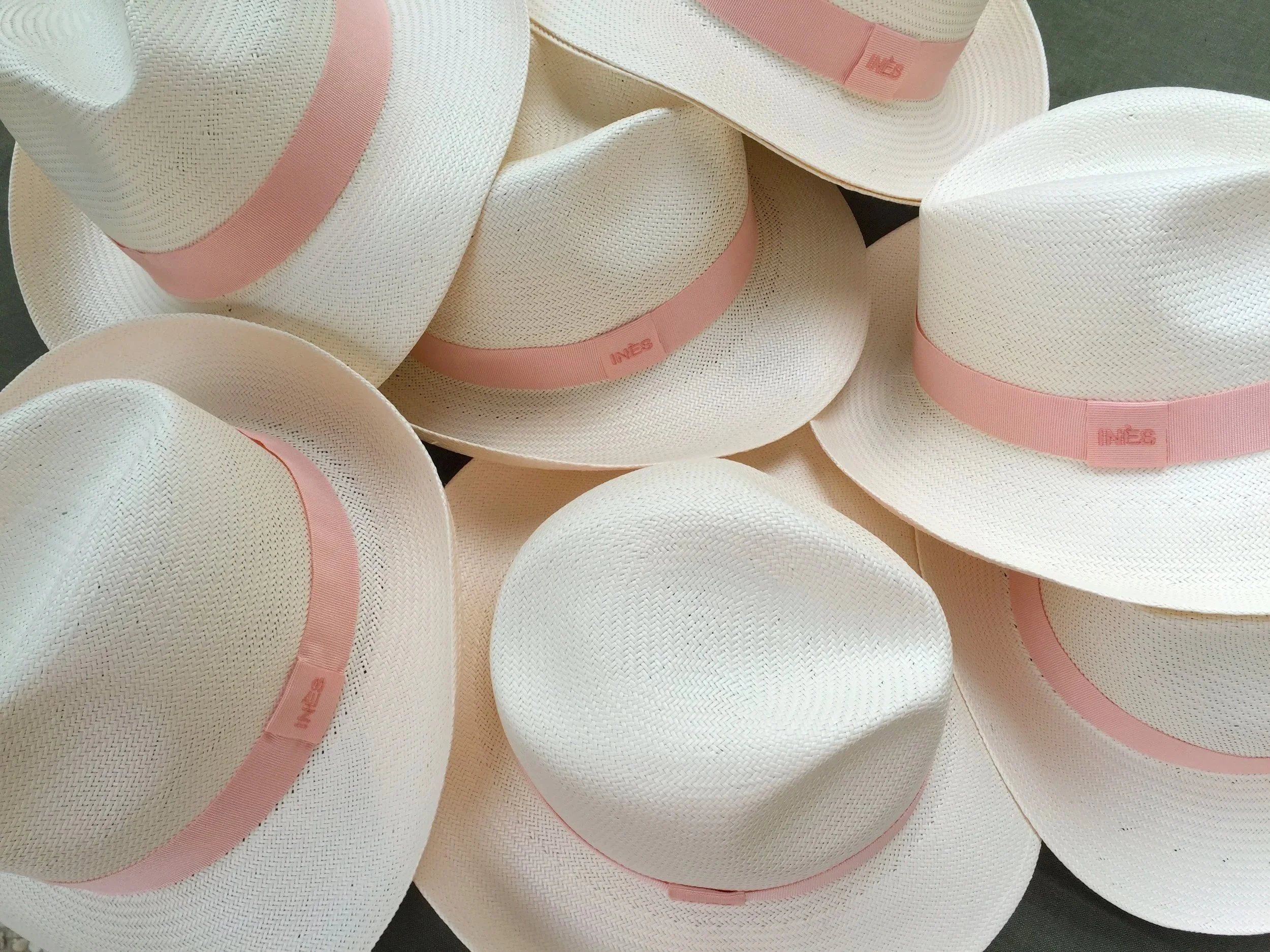 Un ensemble de chapeaux blancs avec des bandes roses, empilés les uns sur les autres.