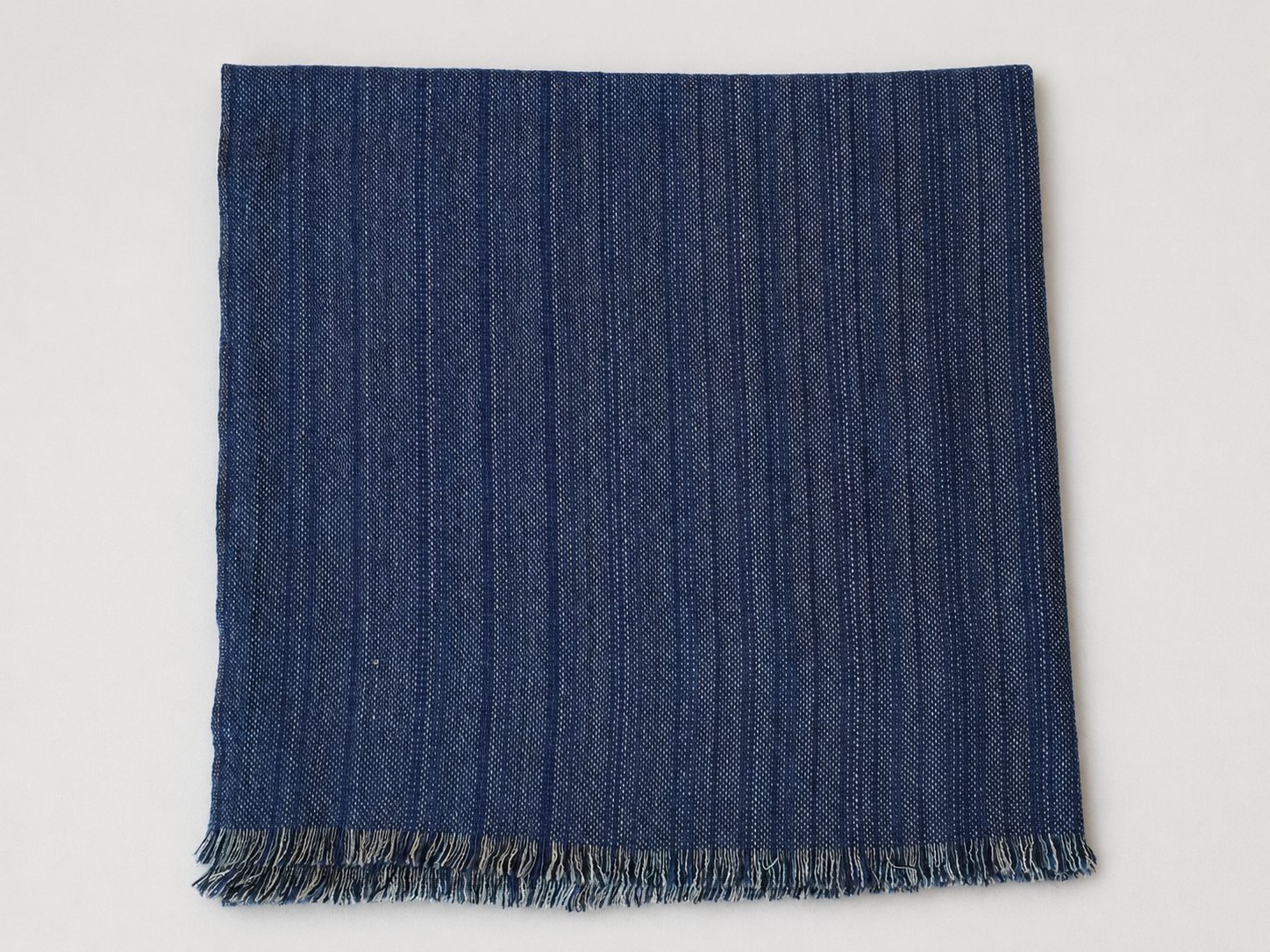 Un tissu bleu foncé à motifs de lignes verticales et des franges en bas.