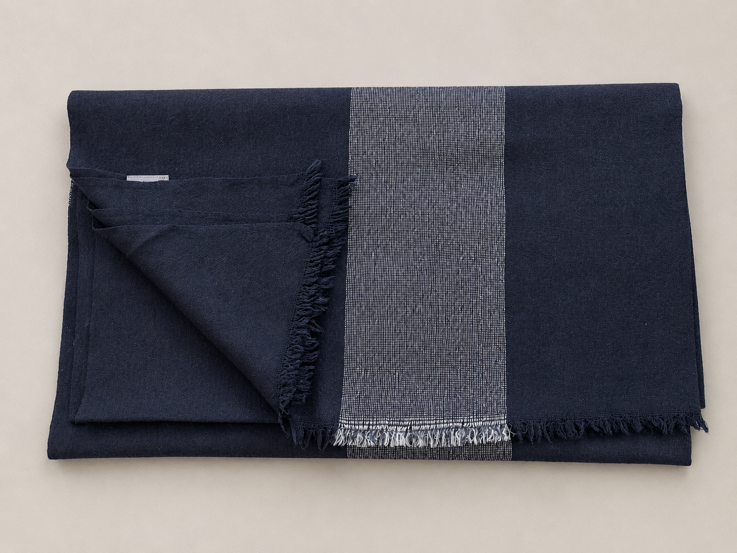 Une nappe ou un tissu bleu plié avec une bande rayée blanc et bleu, posé sur une surface claire.