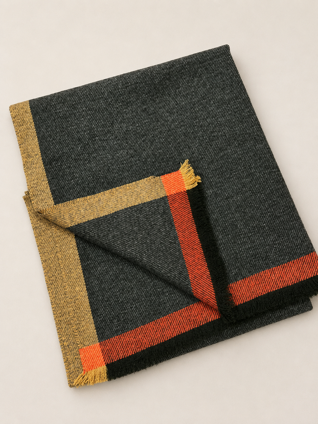 Un foulard en tissu noir avec des bordures en jaune, rouge et noir placé sur fond blanc.