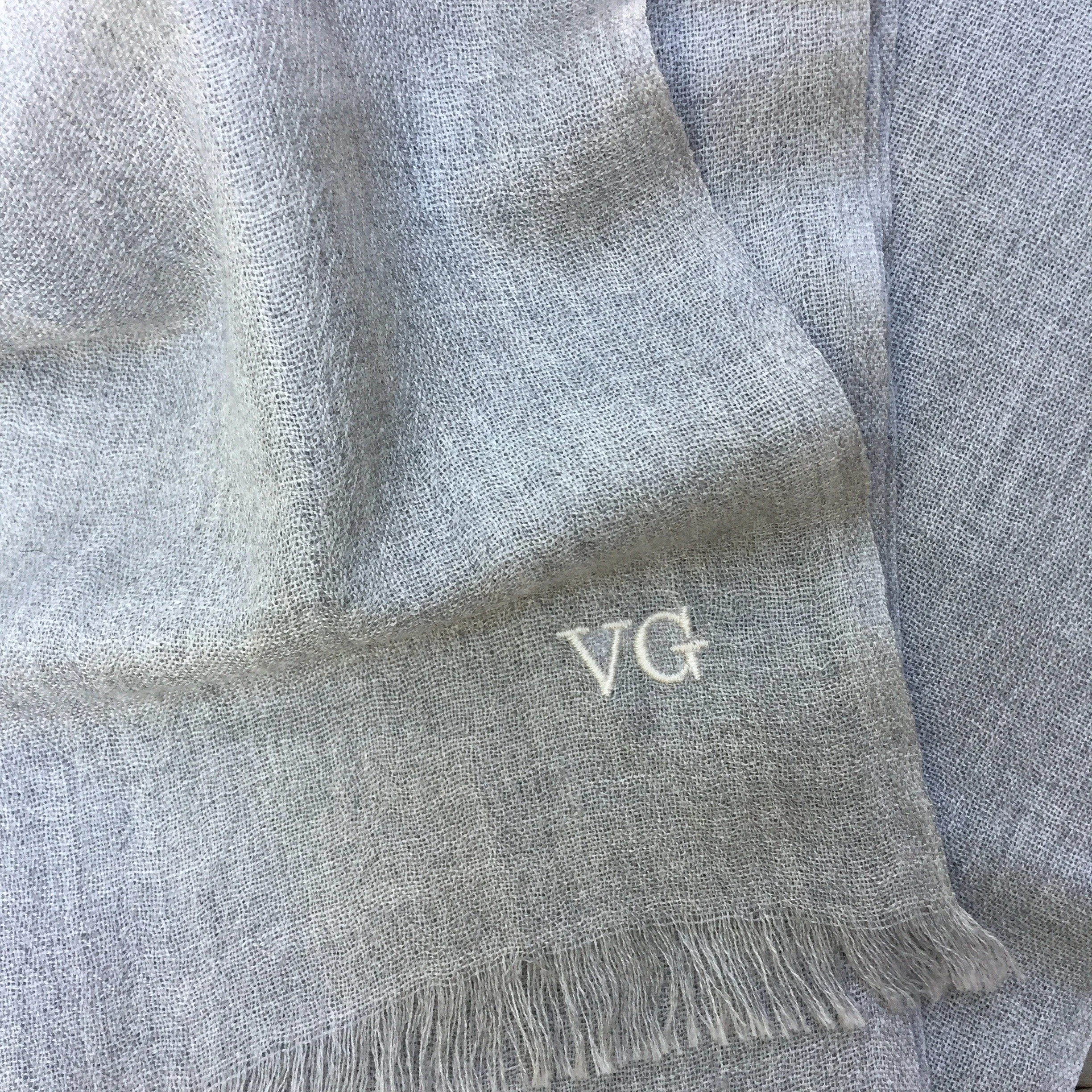 Tissu gris à texture fine avec un logo en bas à droite indiquant 'V.