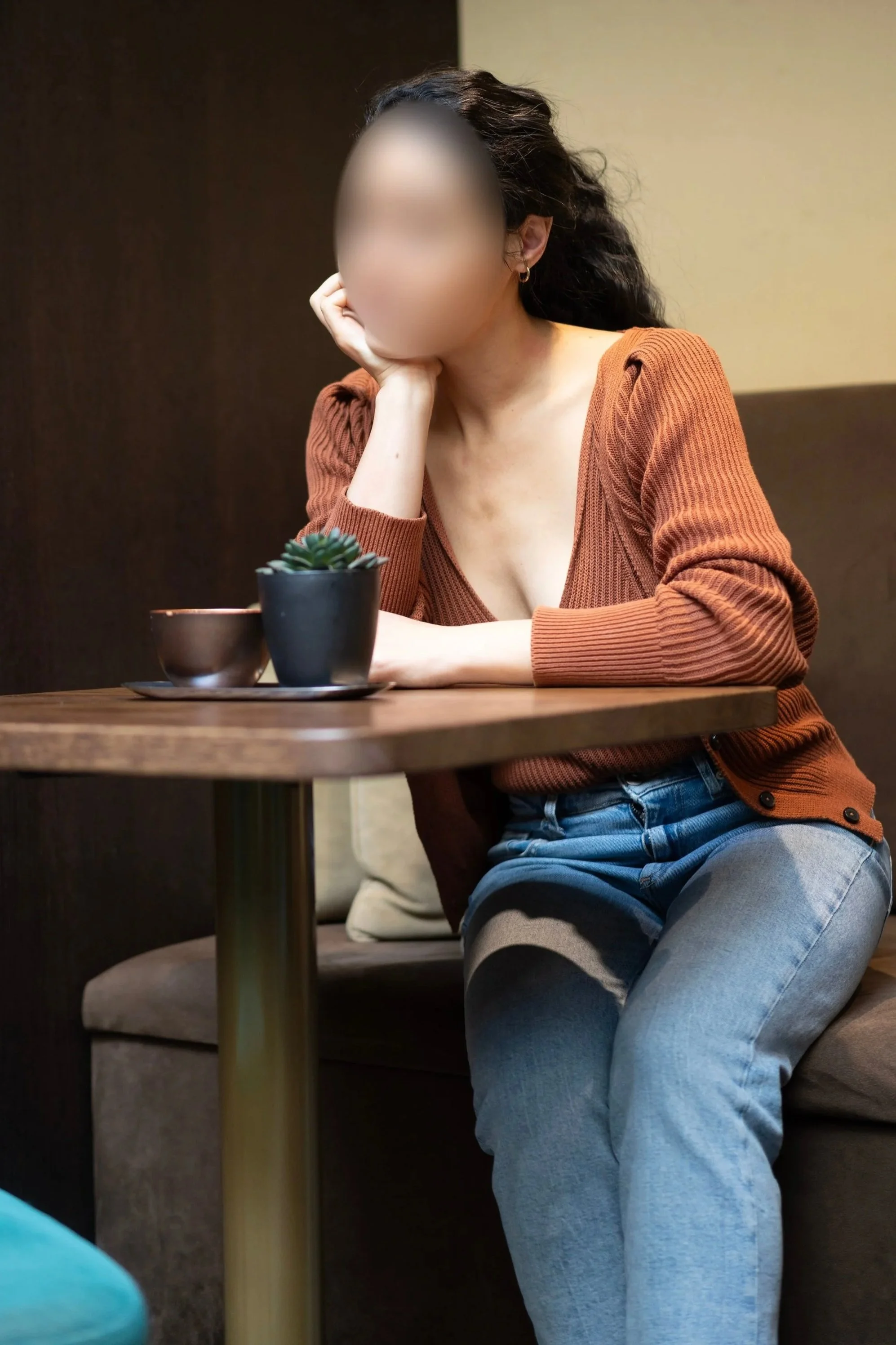 Alice Dorseuil – luxury companion and discreet escort in Geneva, seated at a cozy table in a refined indoor environment
